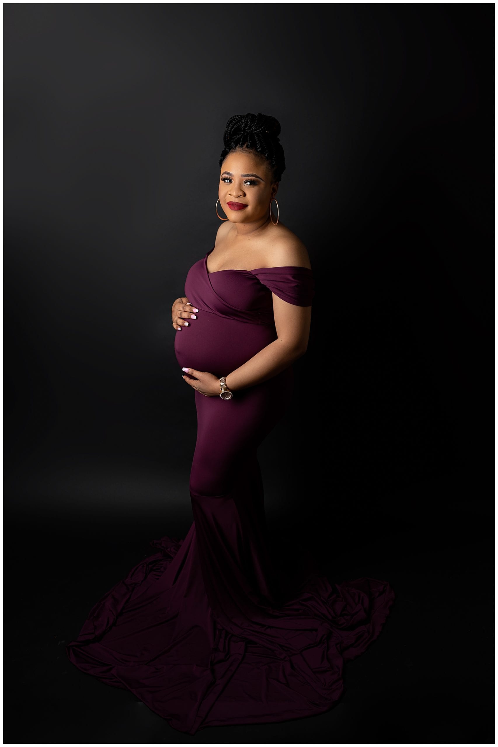pregnant woman wearing a purple dress holding her belly