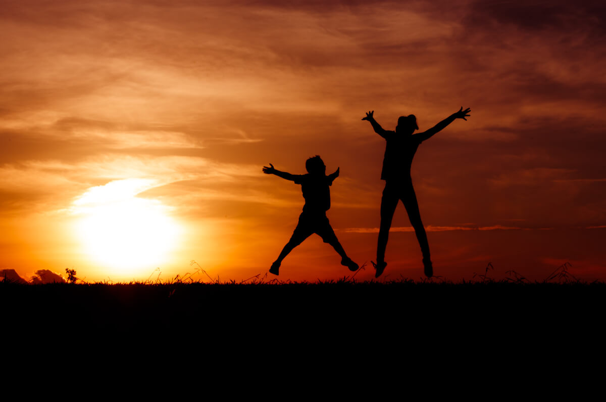 Sunset silhouette of two children jumping