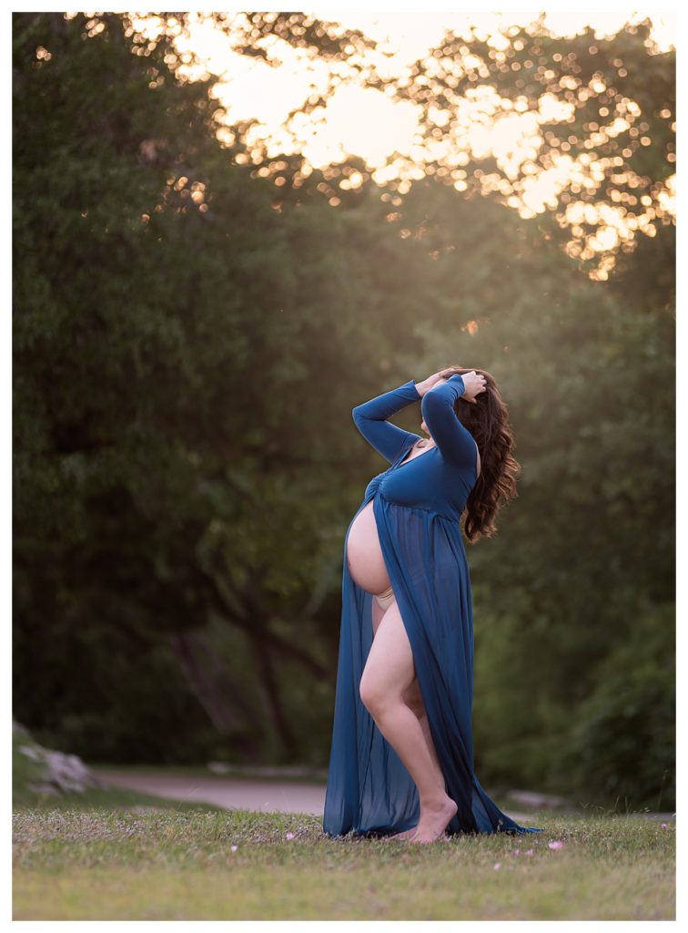 A pregnant woman wearing a teal flowing maternity dress for an artistic photoshoot in Austin, Texas.