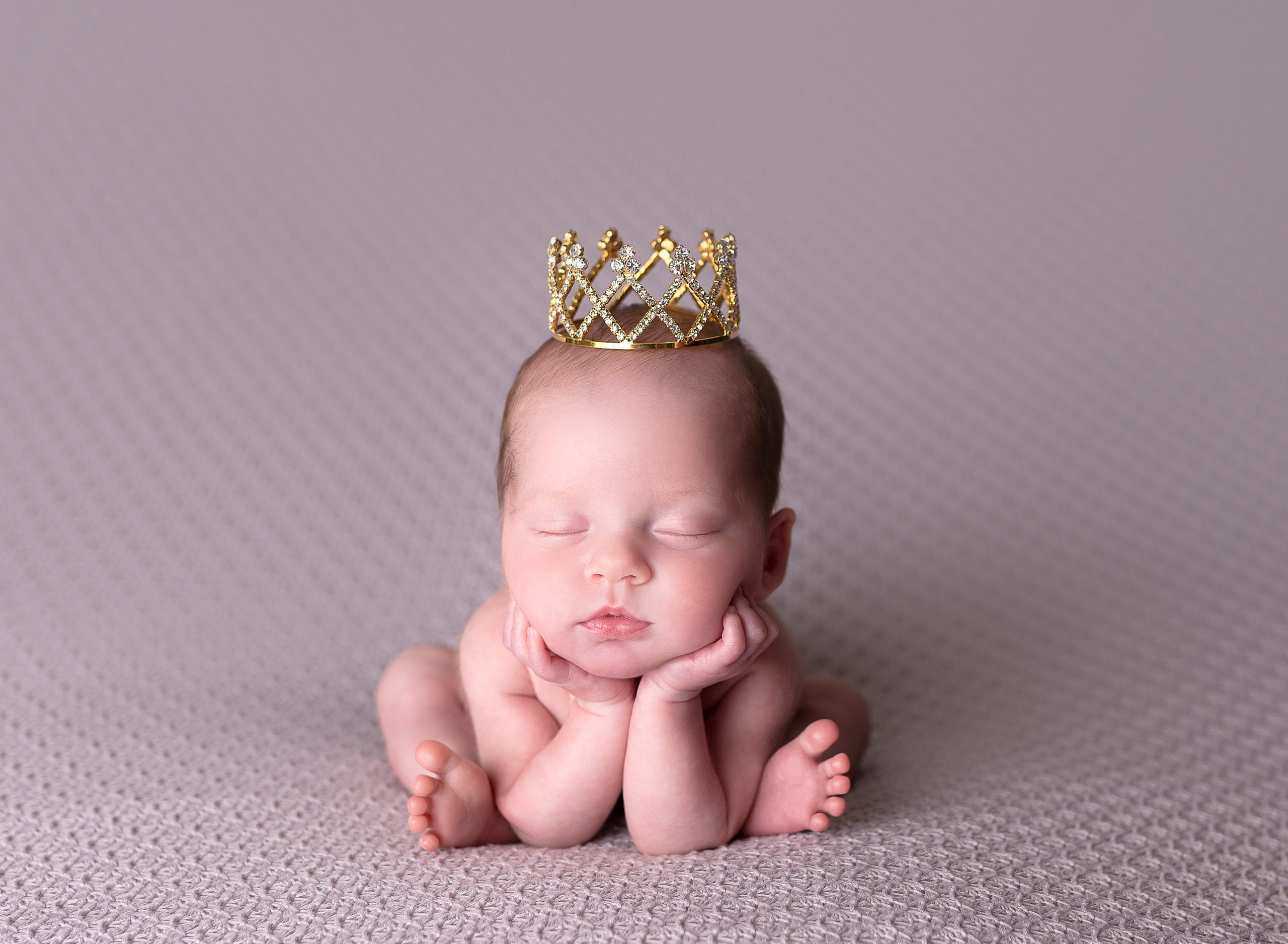 A princess newborn in the froggy pose.
