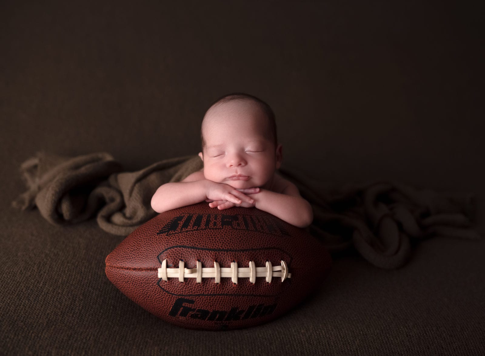 Newborn with a football by Hello Photography