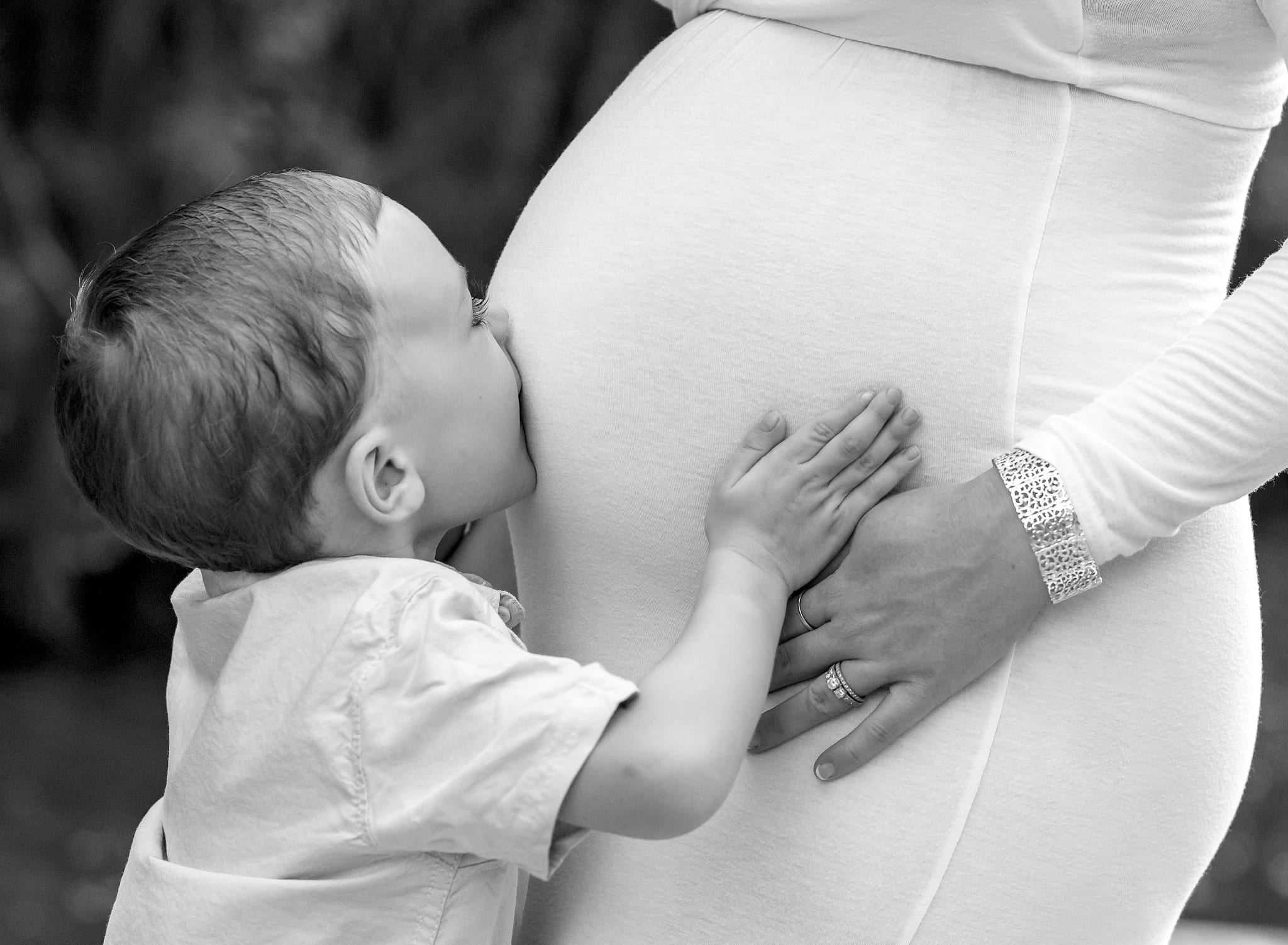 Boy kissing his momma's belly.