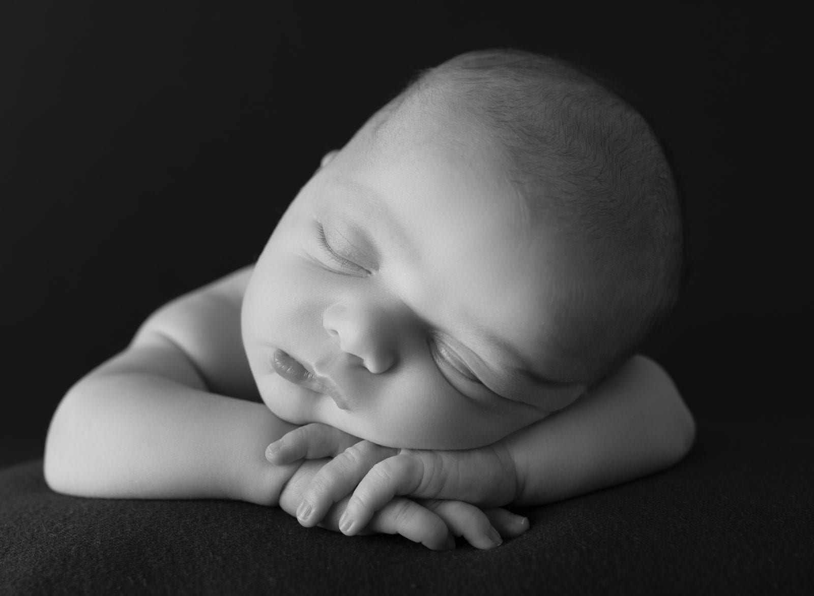 sleeping newborn baby with his head on his hands