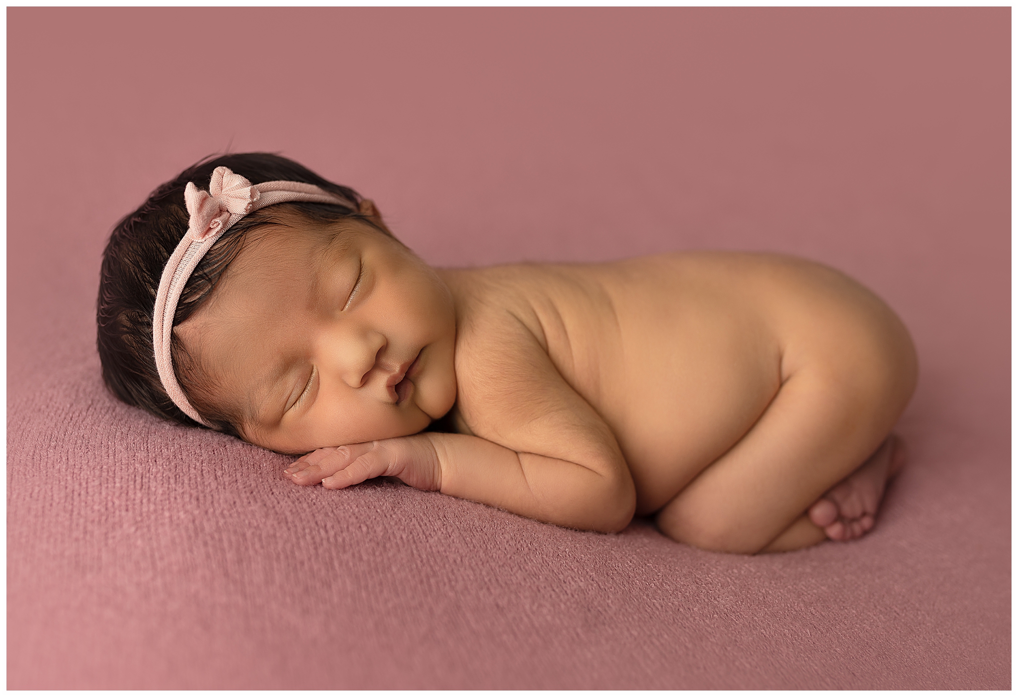 newborn baby girl sleeping on a pink blanket