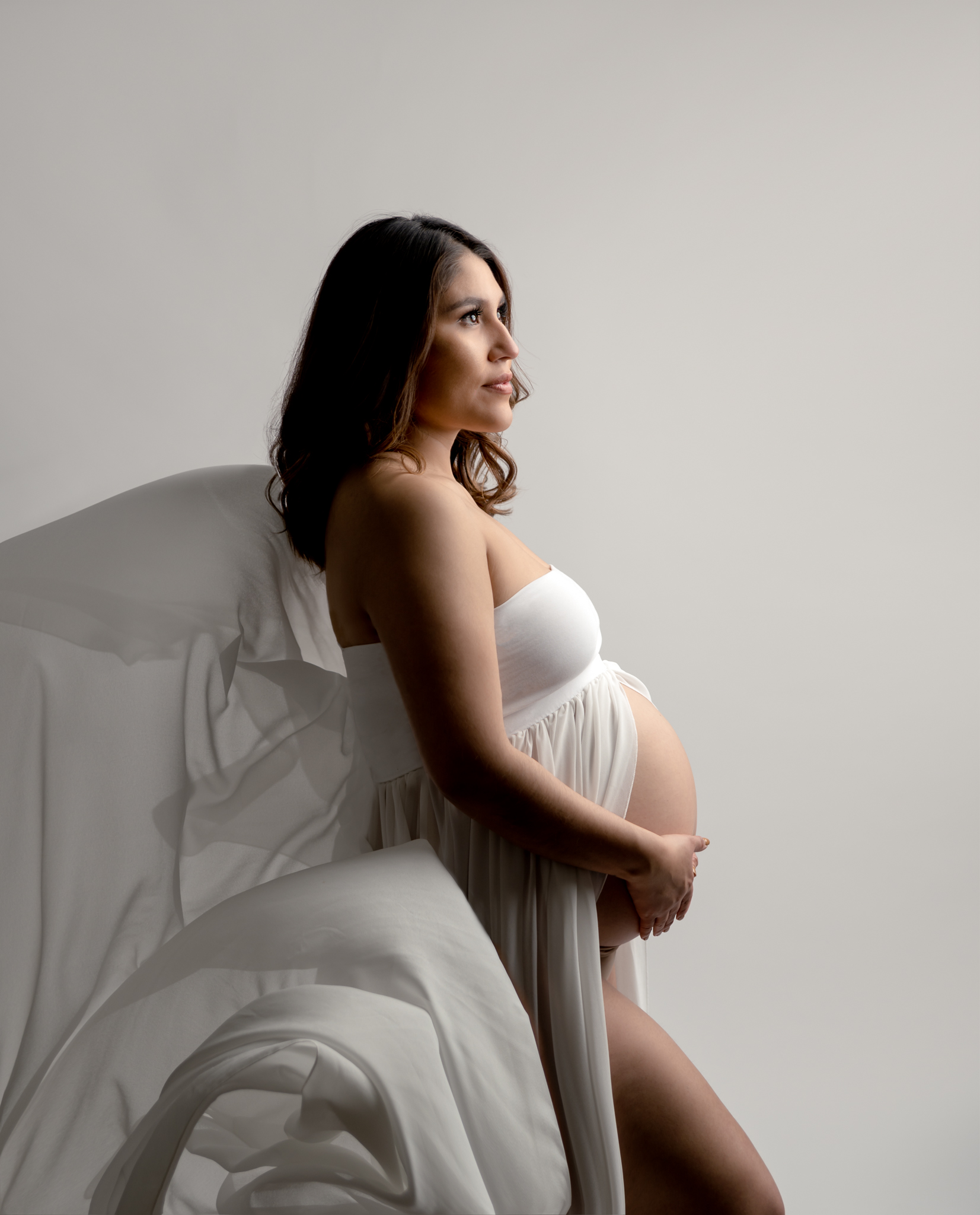 maternity photo of a woman in a white flowy dress