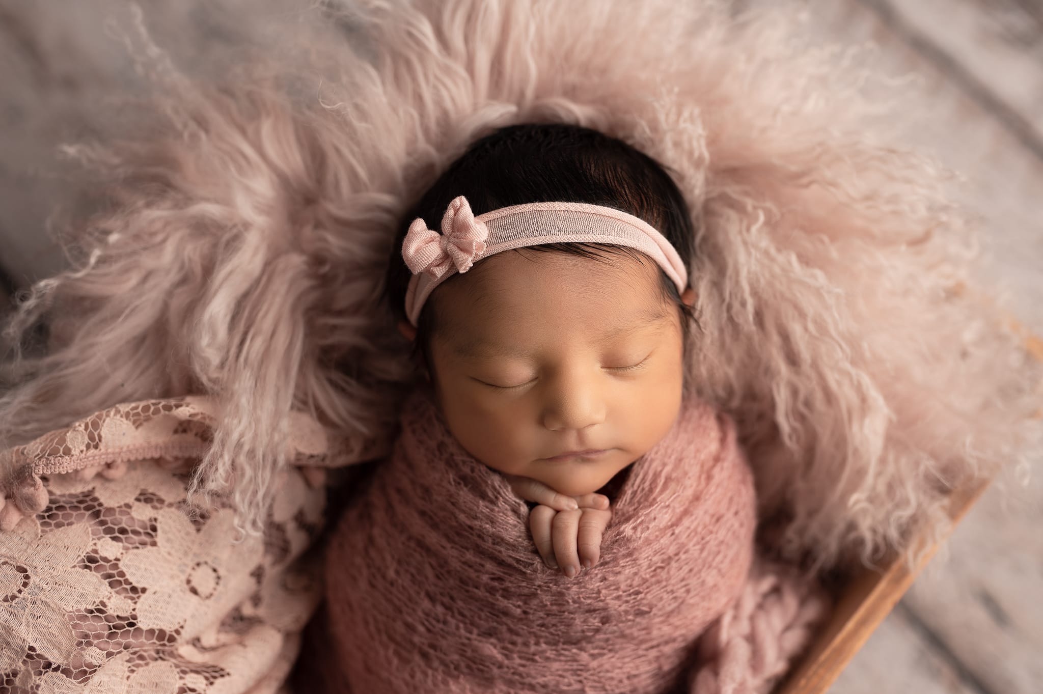 newborn baby wrapped in pink textures