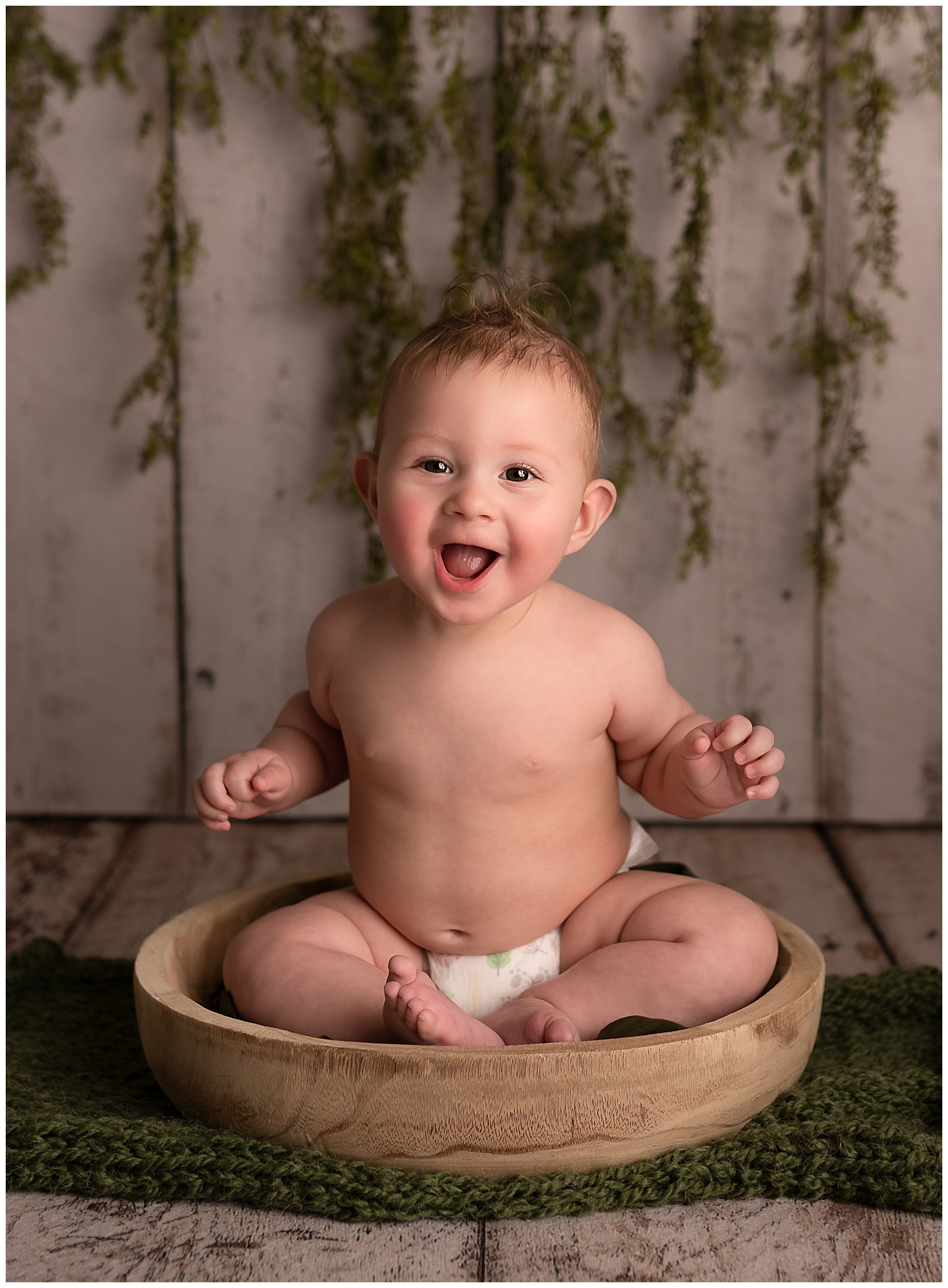 happy baby sitting in a wooden bowl