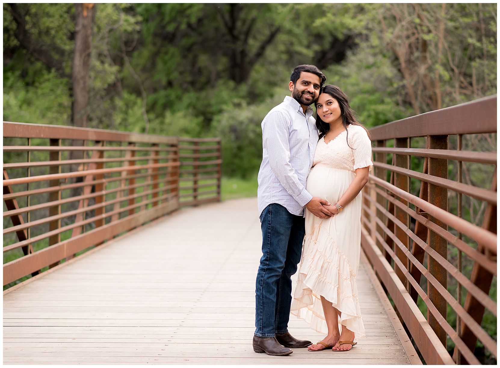 husband and pregnant wife on a bridge