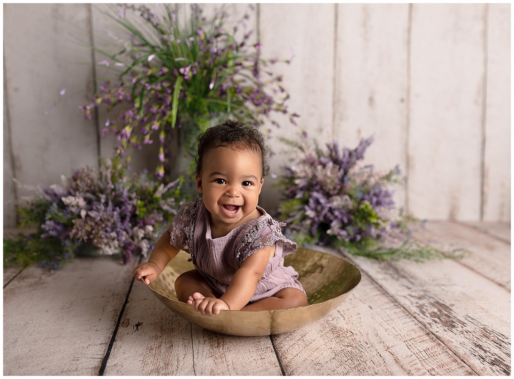 happy baby girl in a gold bowl with purple flowers