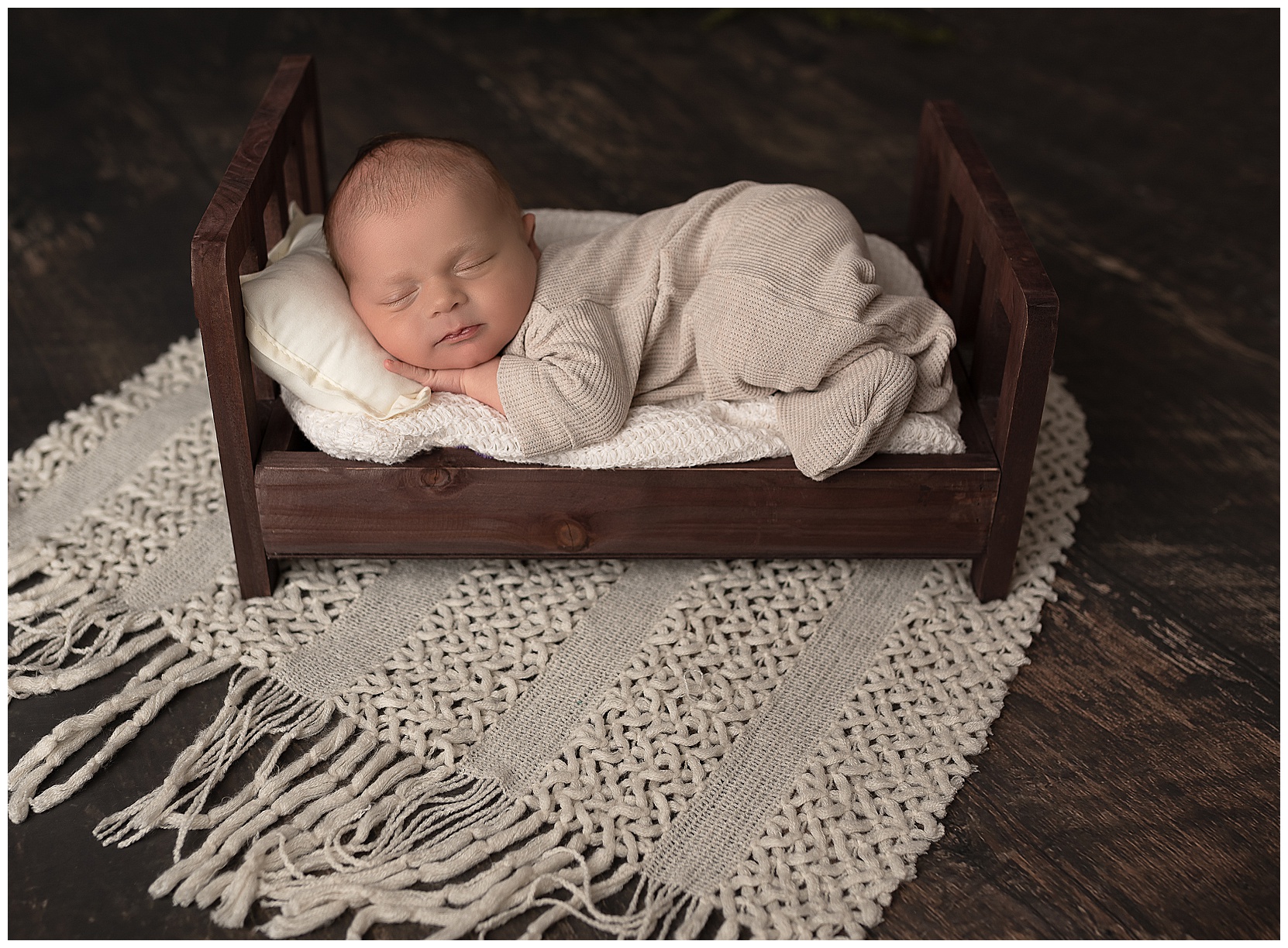 newborn baby sleeping in a tiny brown bed