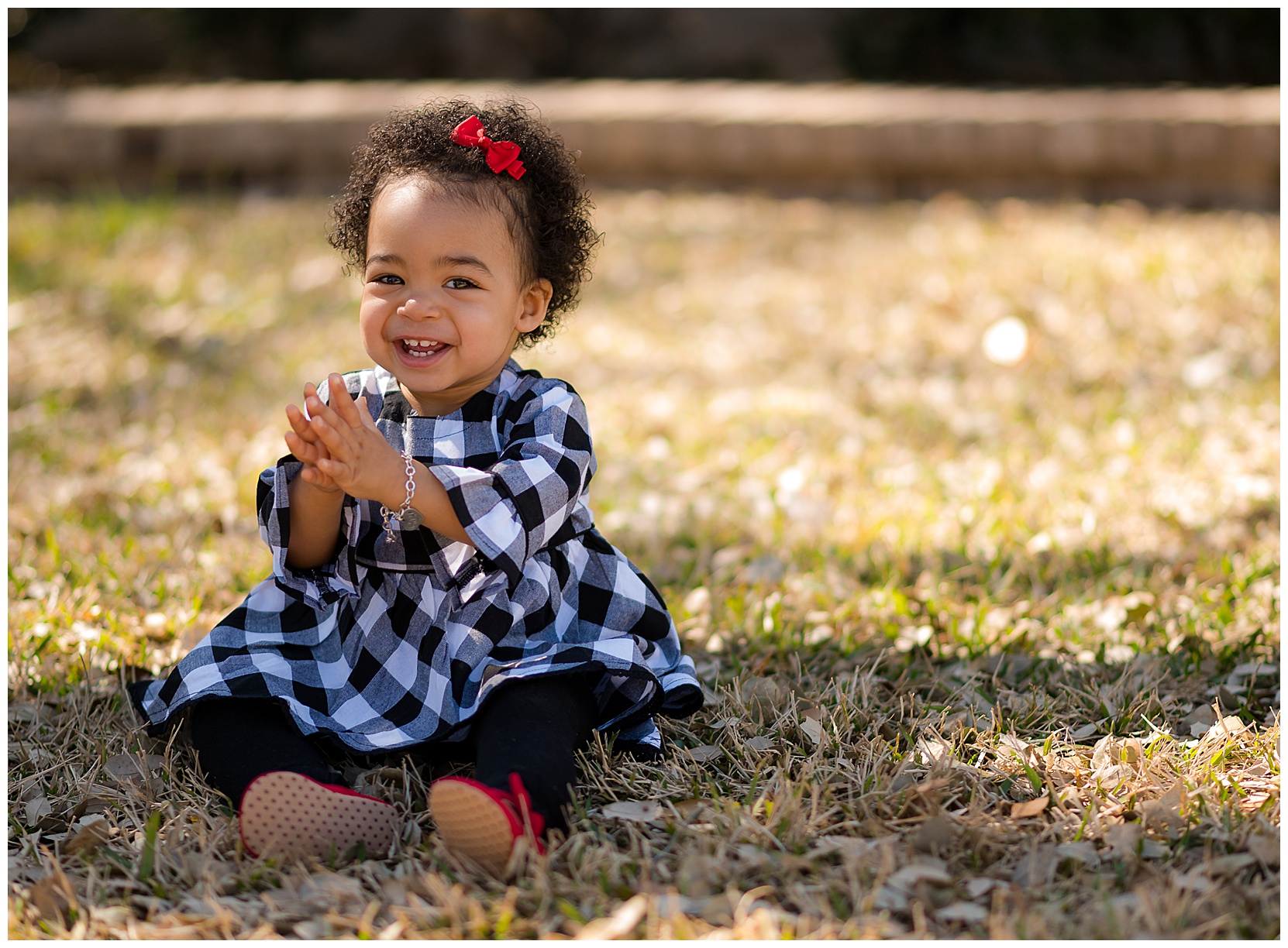happy baby wearing a black and white checkered dress with red headband