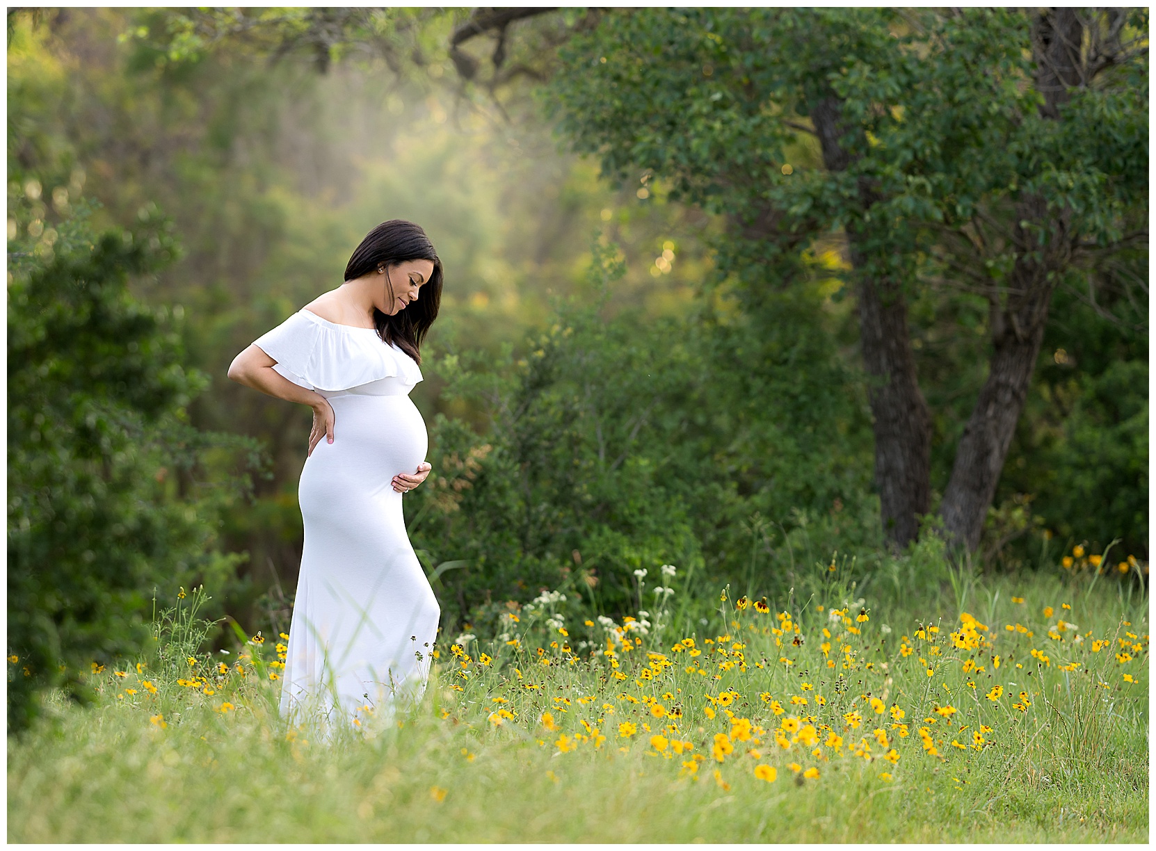 pregnant woman wearing a white dress in a field of yellow wildflowers