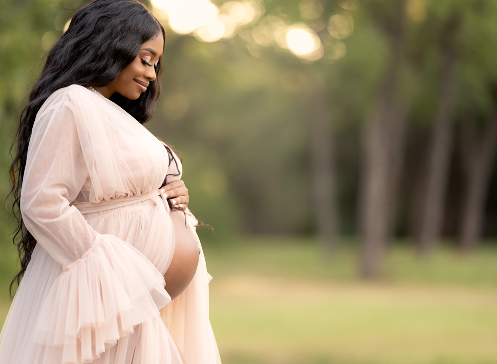 a pregnant woman wearing a pink tulle dress in the park