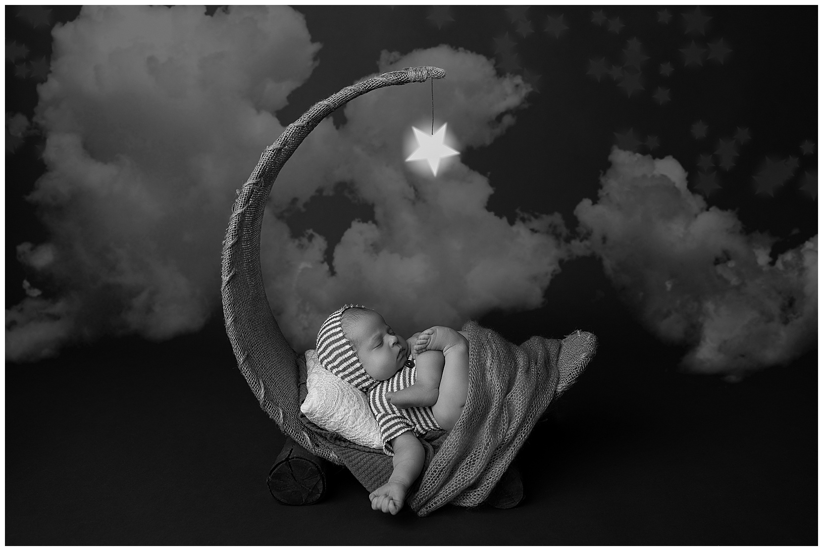 black and white photo sleeping baby on a moon prop