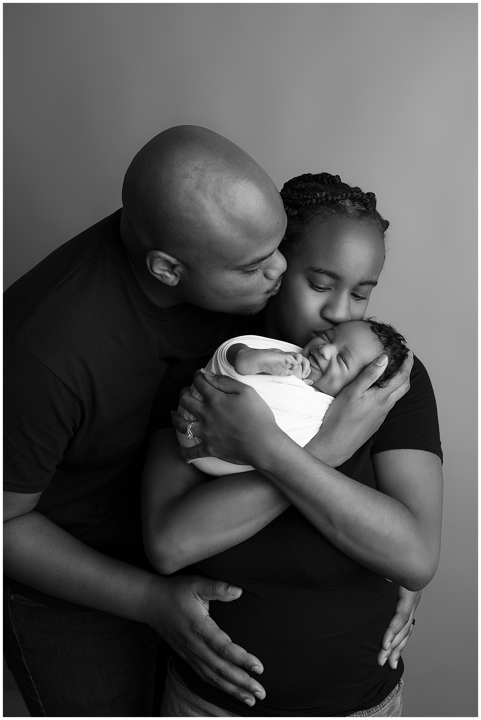 parents holding baby girl in black and white