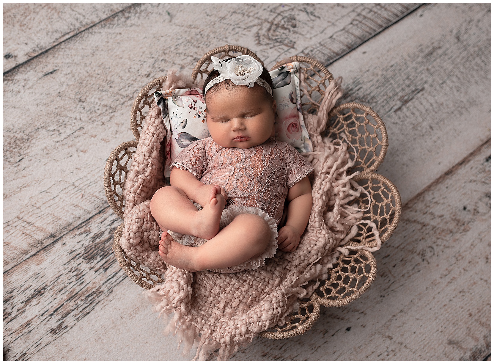 sleeping baby girl wearing a lace romper sleeping in a flower bowl
