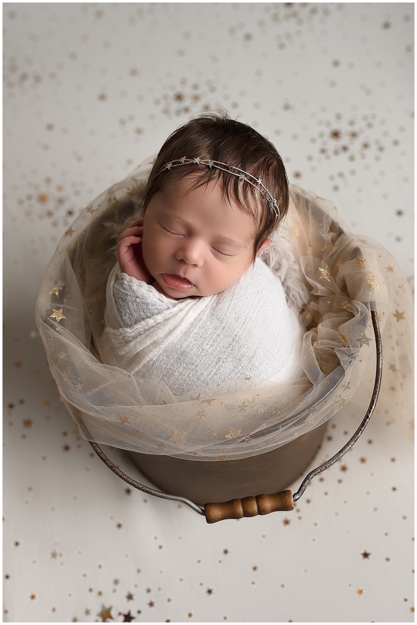 sleeping baby in a brown bucket with stars in the background