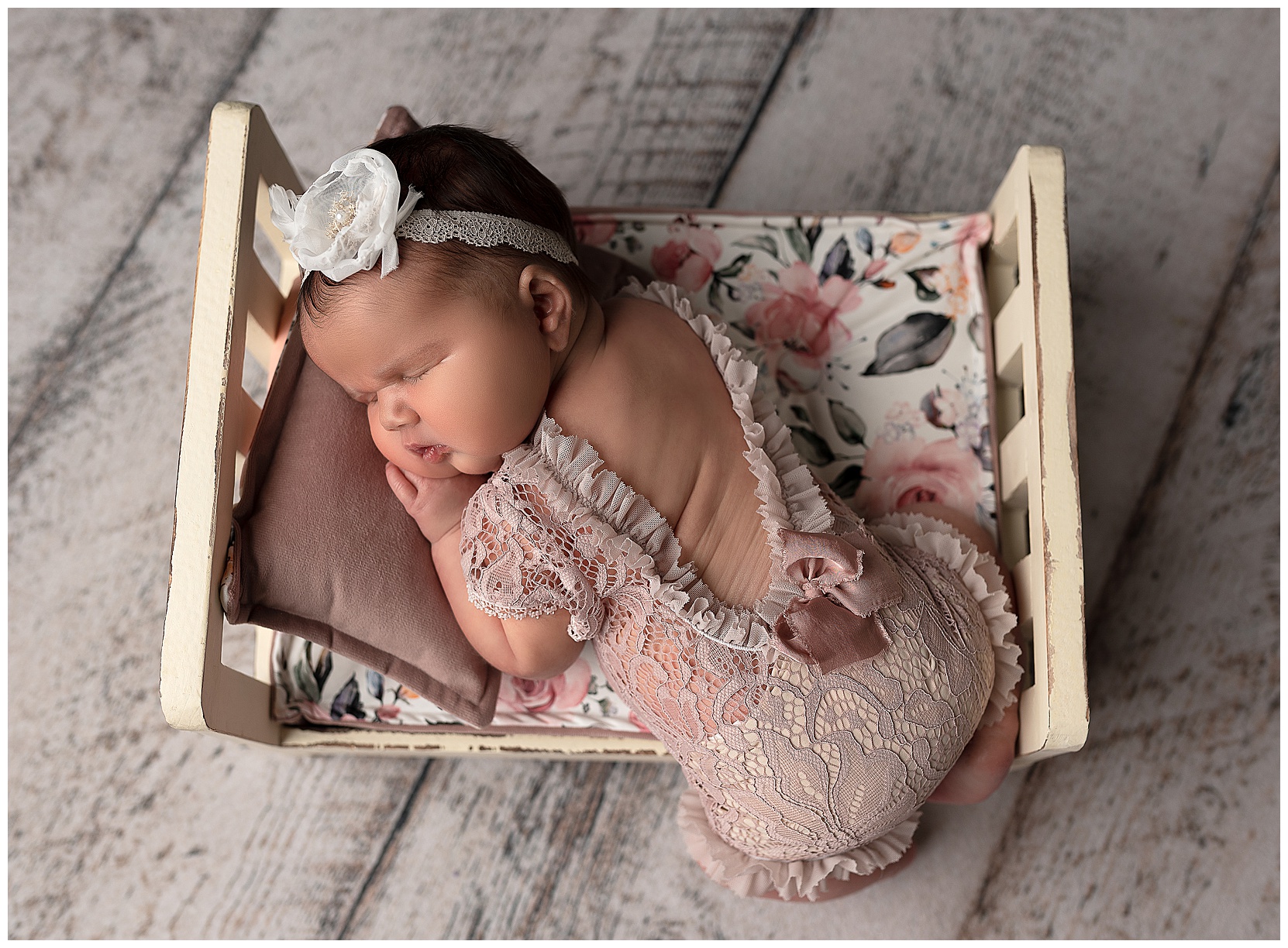 sleeping baby girl wearing a lace romper sleeping ion a white baby bed