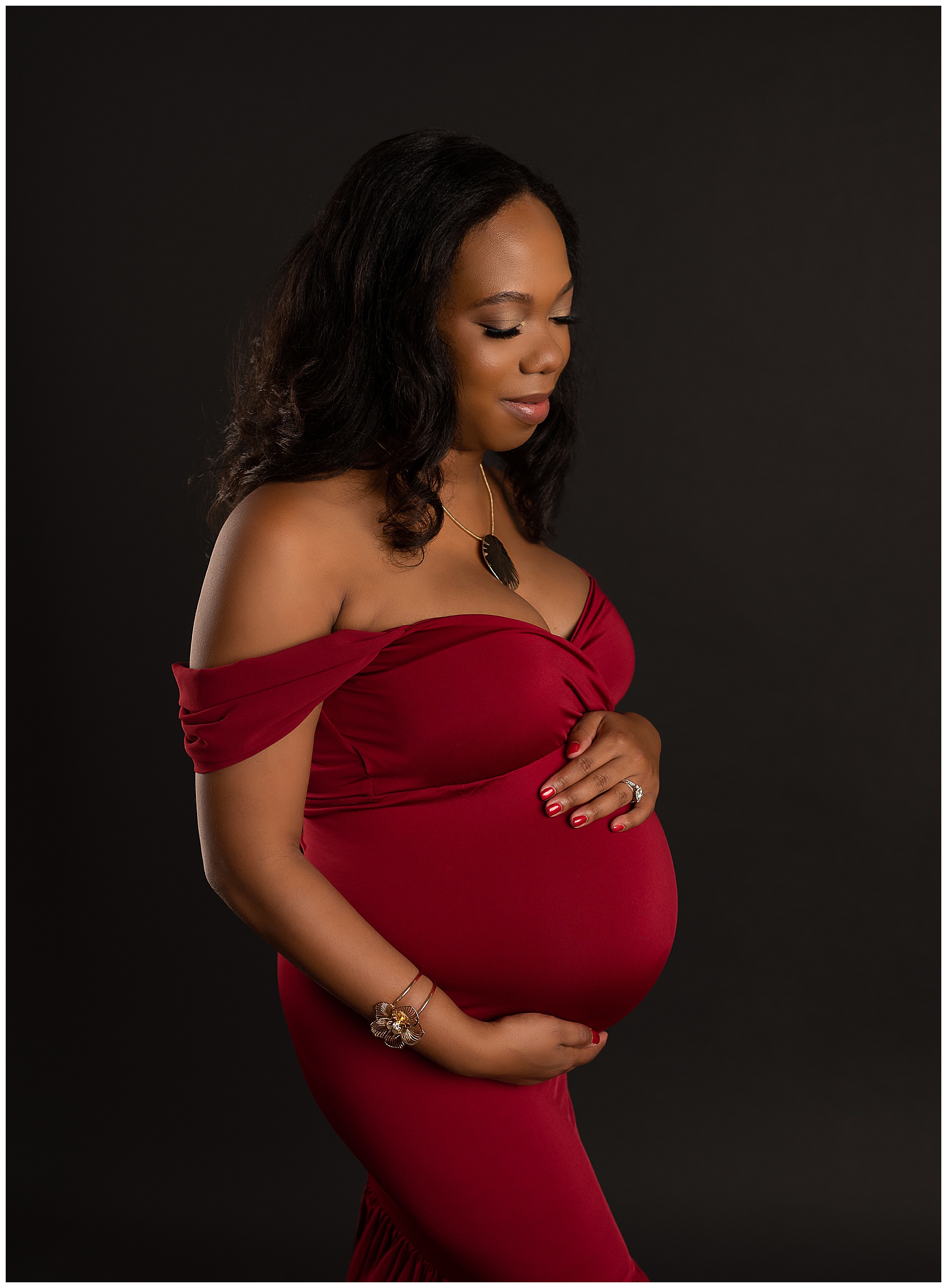 pregnant woman wearing a red dress holding her belly