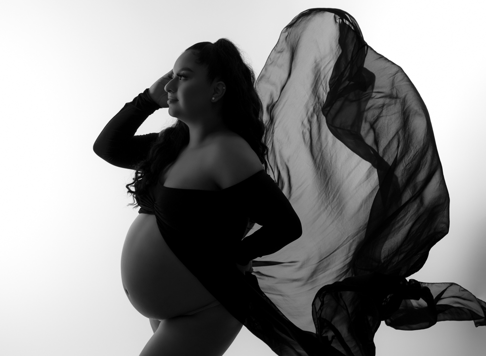 pregnant woman wearing a black dress with fabric flowing behind her