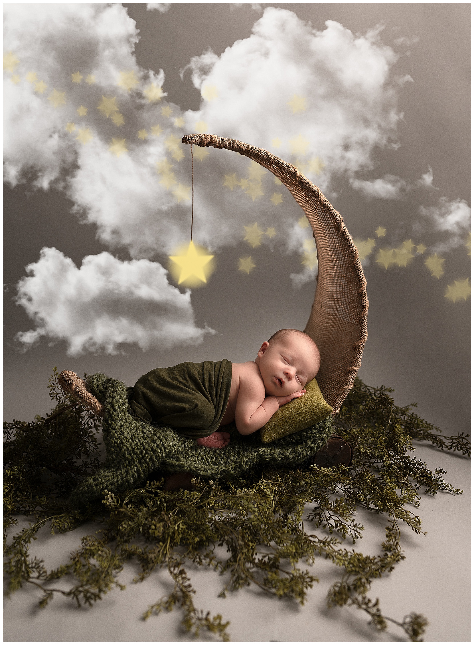 baby sleeping on a moon prop surrounded by clouds and stars.
