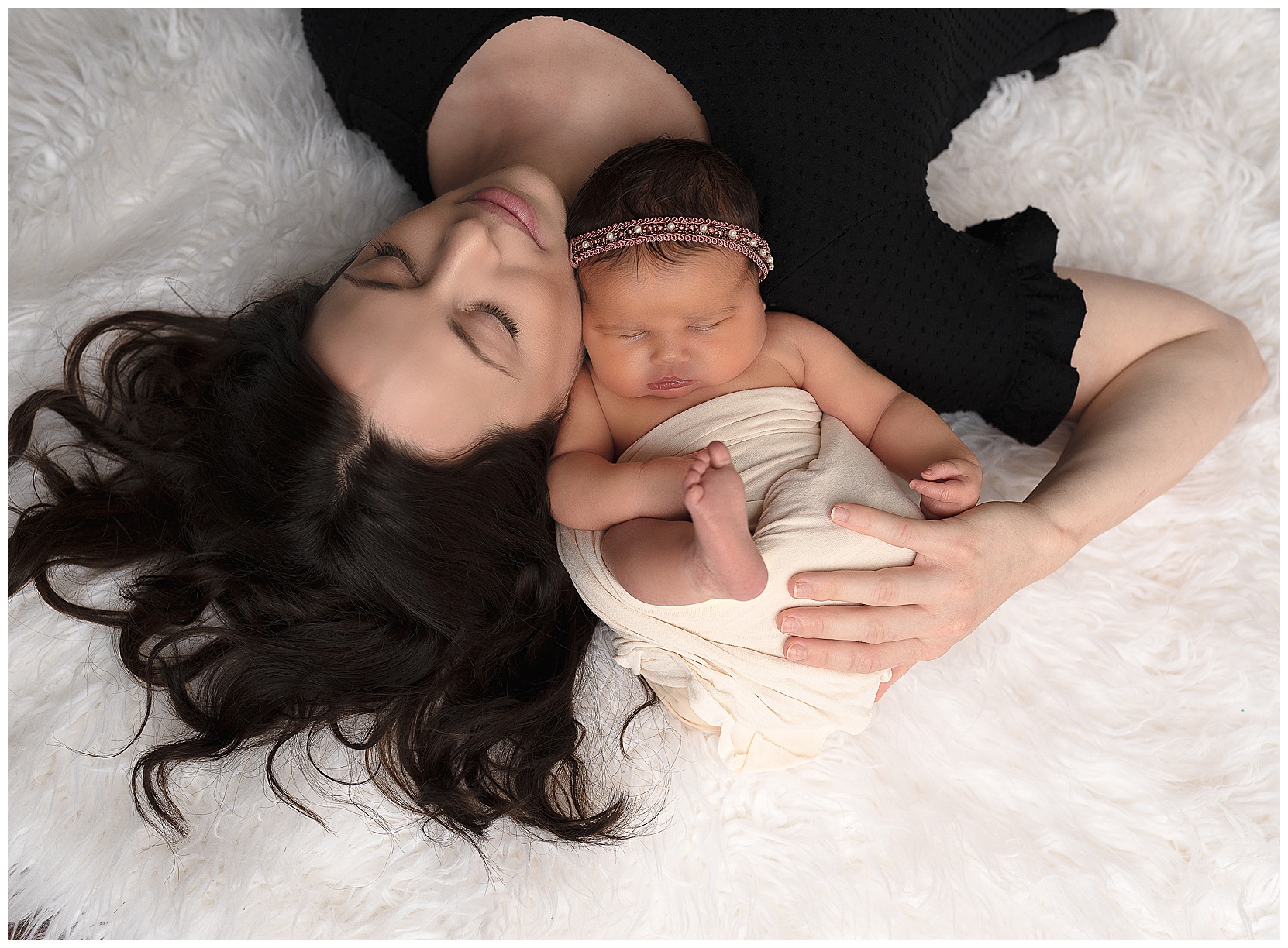 mom sleeping on a white rug holding her sleeping baby girl