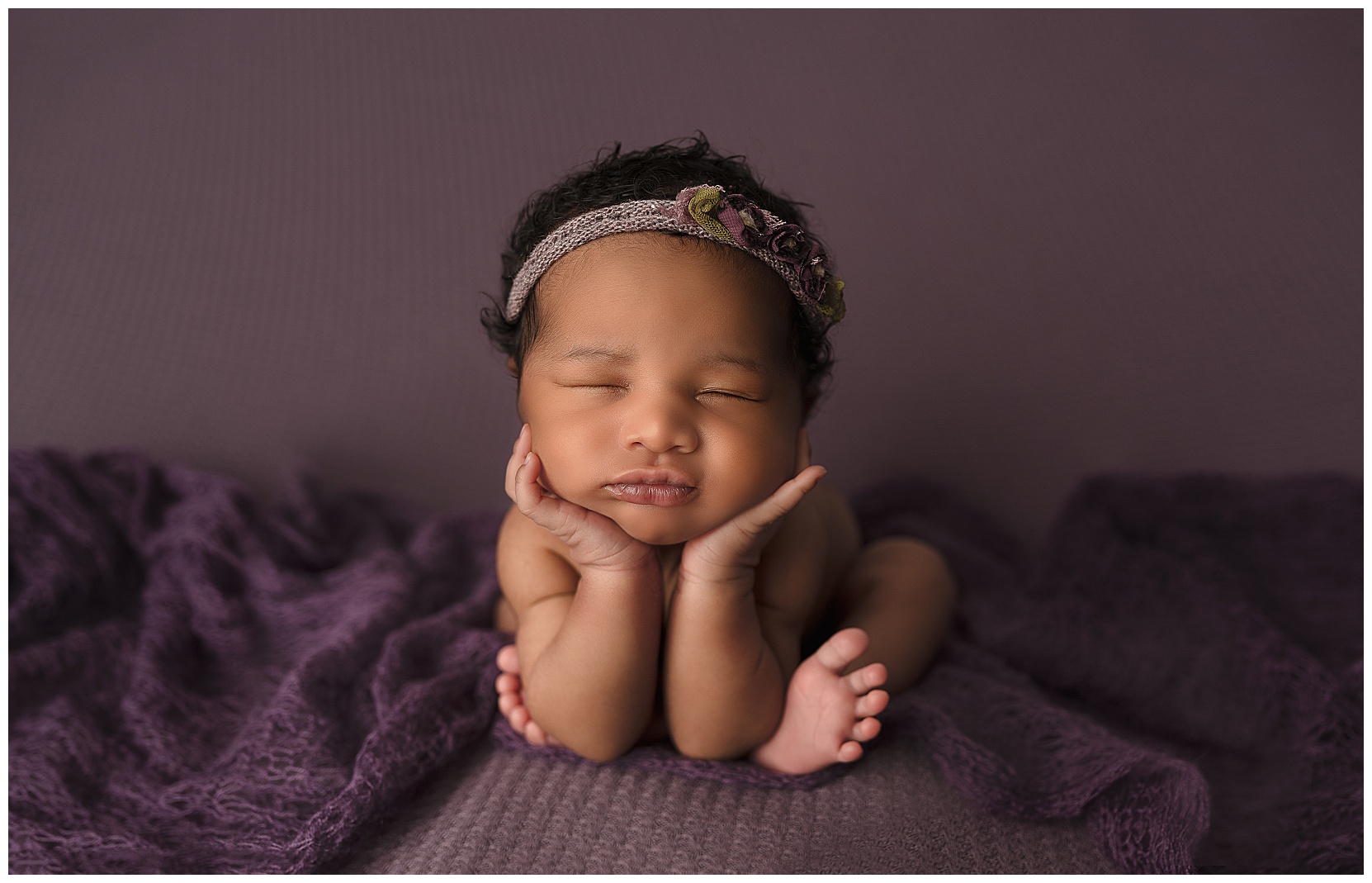 baby girl sleeping in the froggy pose on a purple blanket