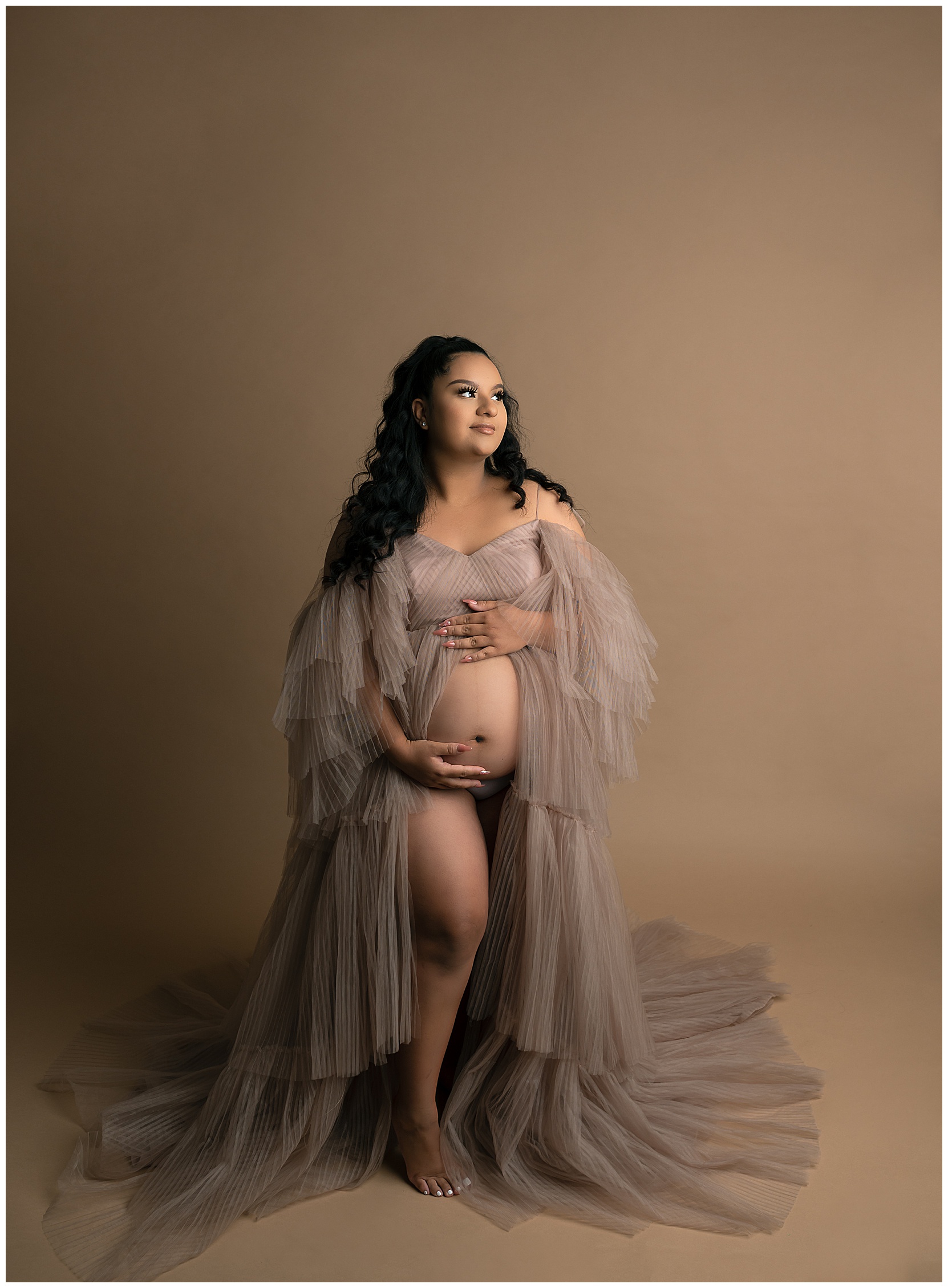 pregnant woman wearing a pink tulle dress holding her belly