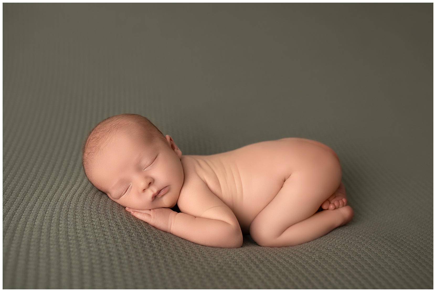 naked newborn sleeping on a green blanket