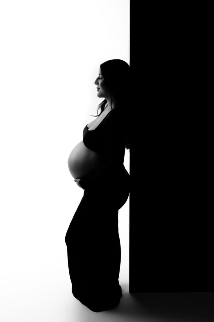 Creative maternity photography Austin featuring artistic silhouette and studio backdrop
