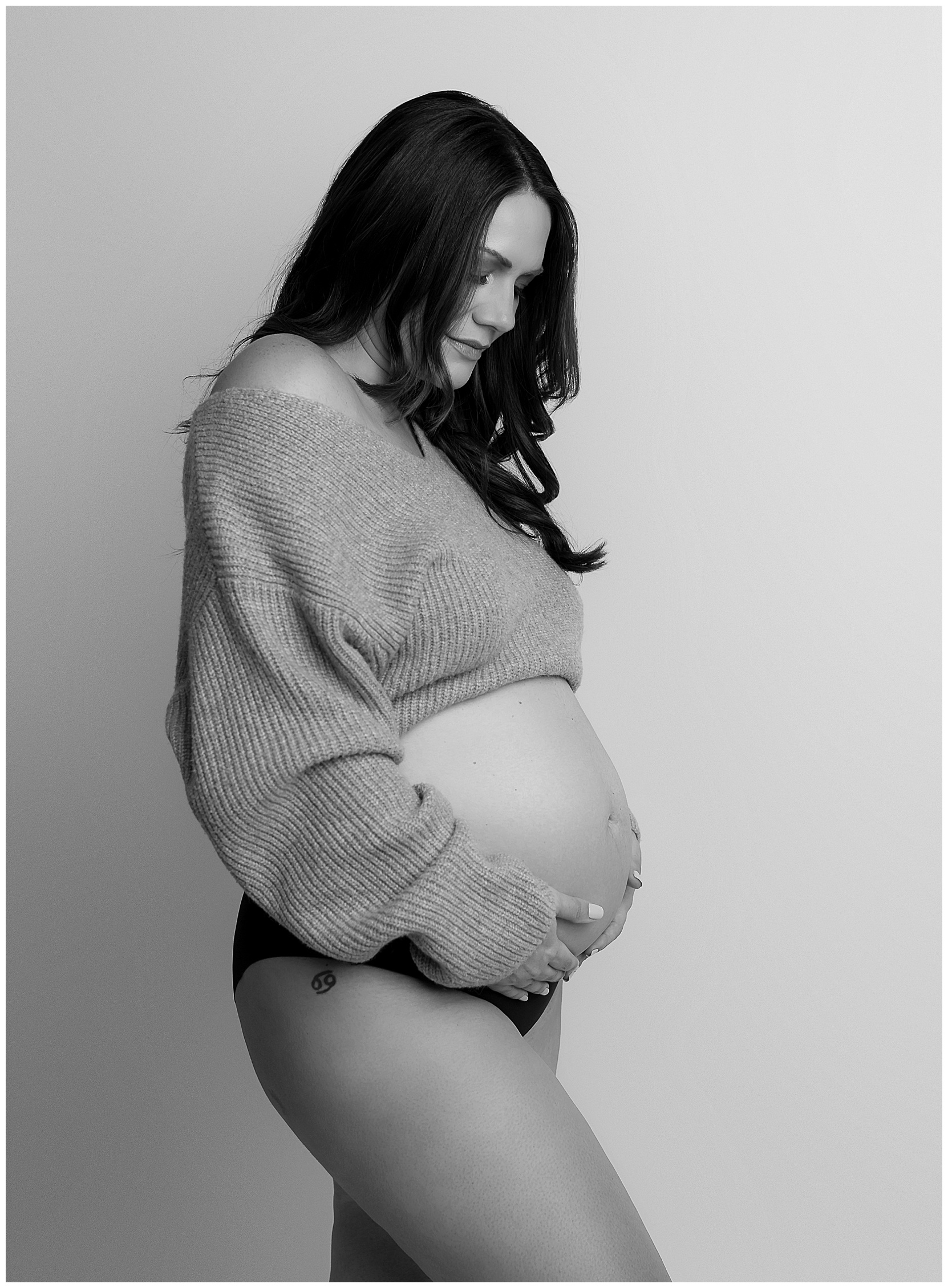 pregnant woman holding her belly with sweater on
