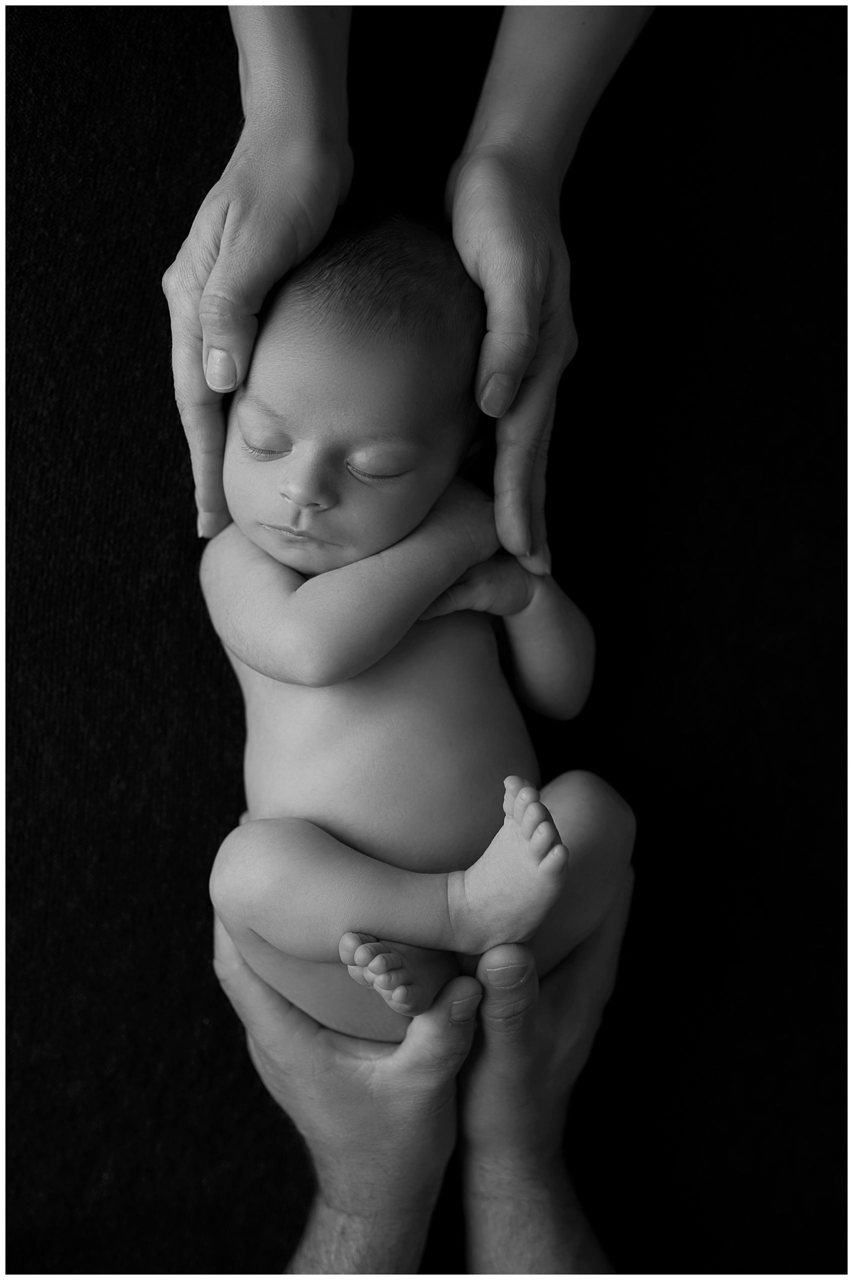 sleeping baby held by mom and dad hands