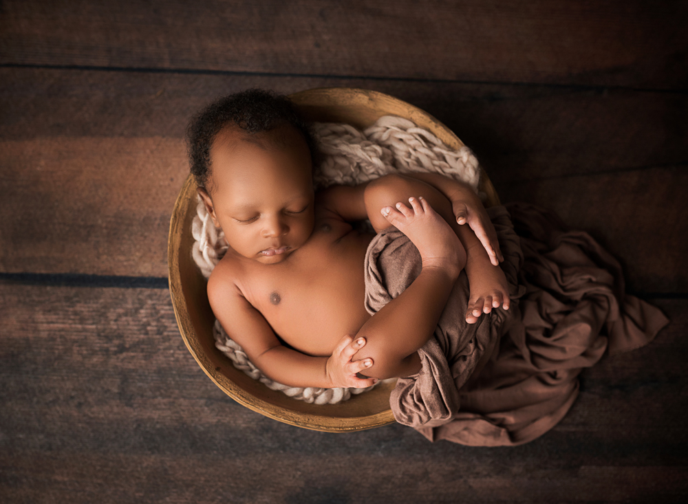 baby in a brown bowl on a wooden floor