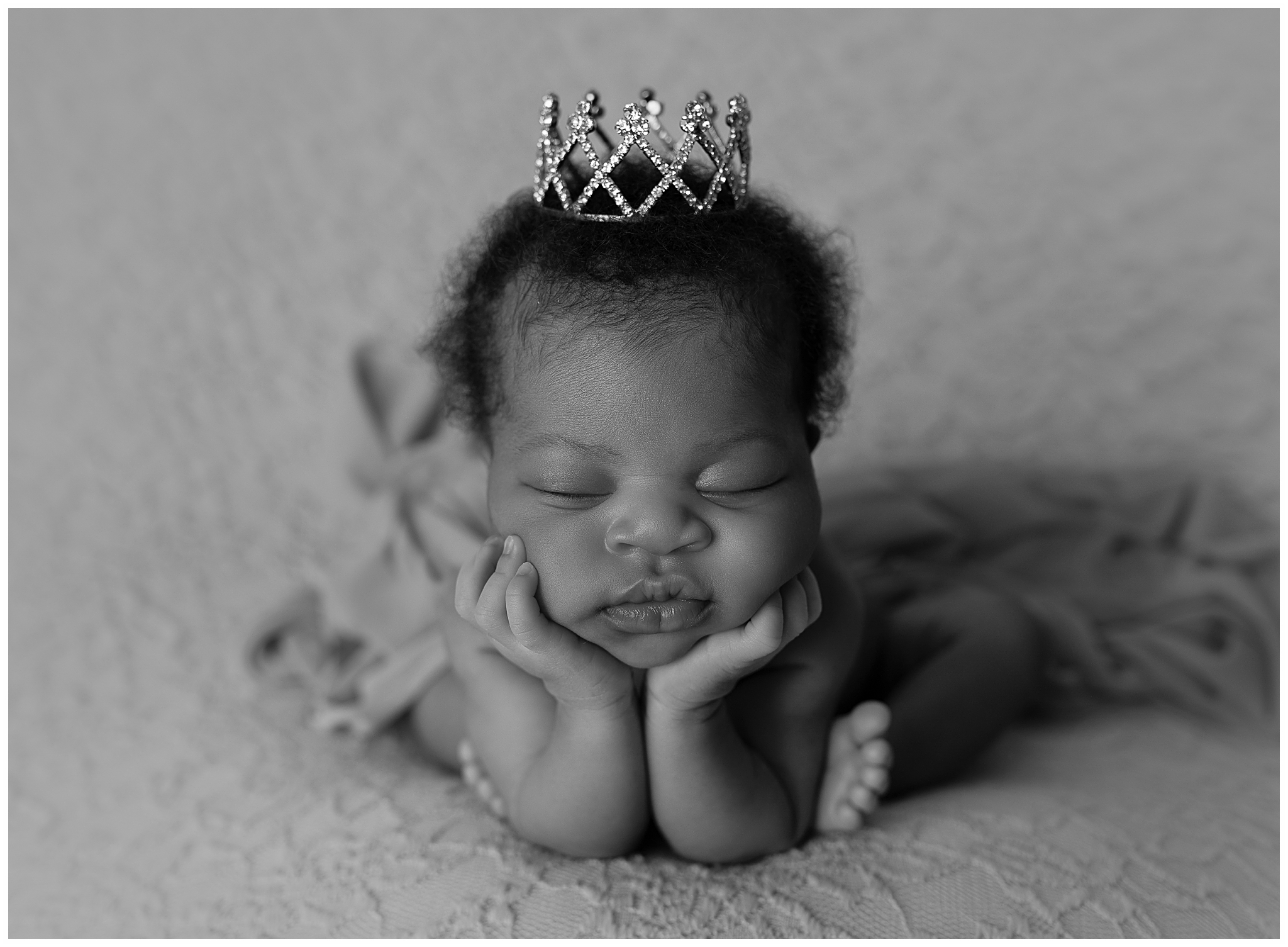 Black and white newborn photo featuring an African American baby in froggy pose wearing a mini tiara