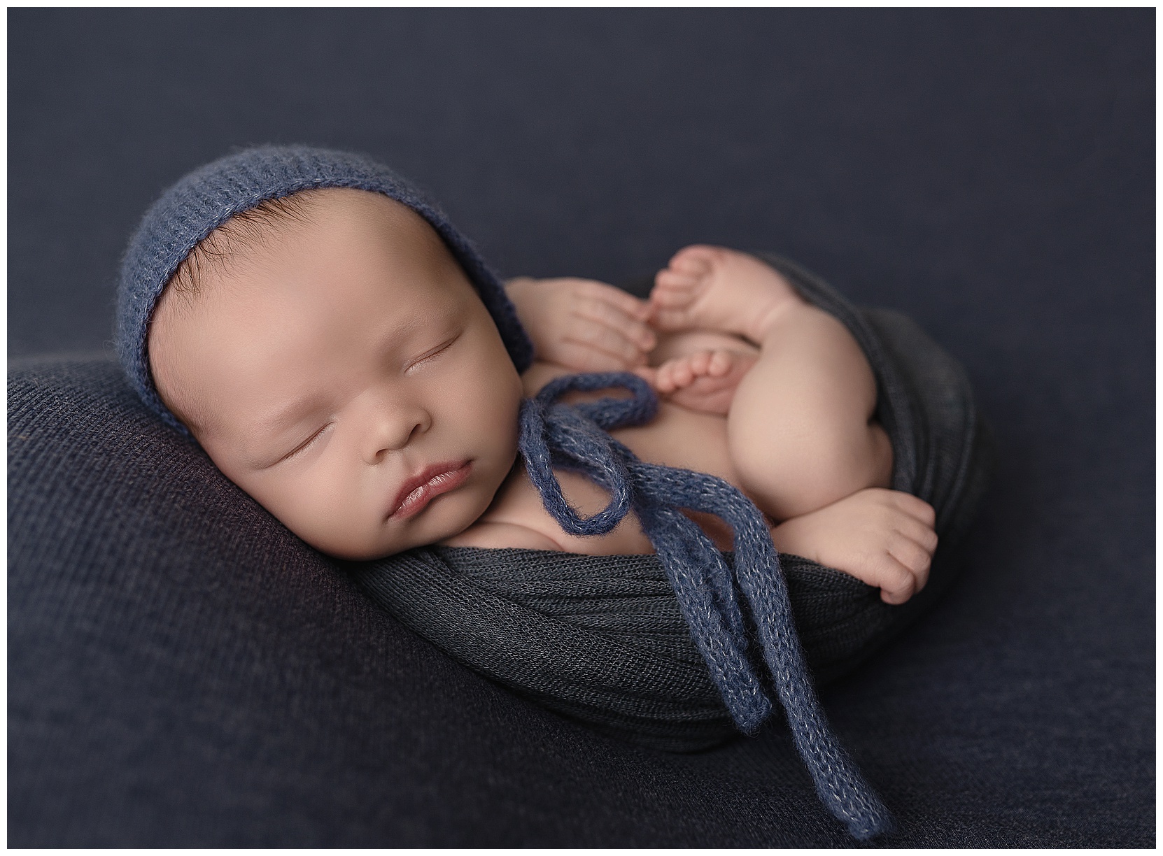 Fair skinned baby on navy blue Jersey knit background wearing blue knit outfit
