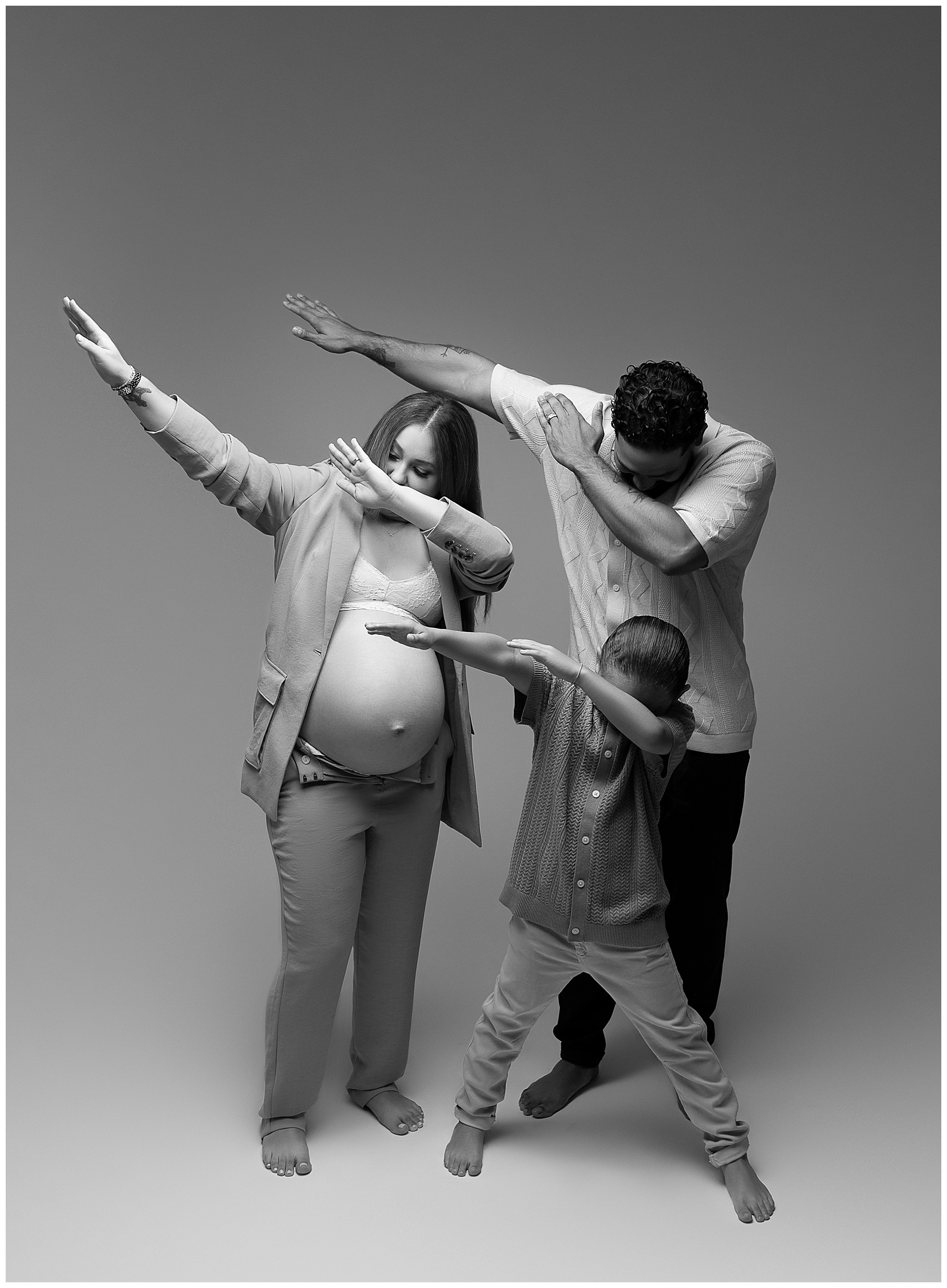 Black and white family photo featuring a man, woman, and child dabbing (dance move)