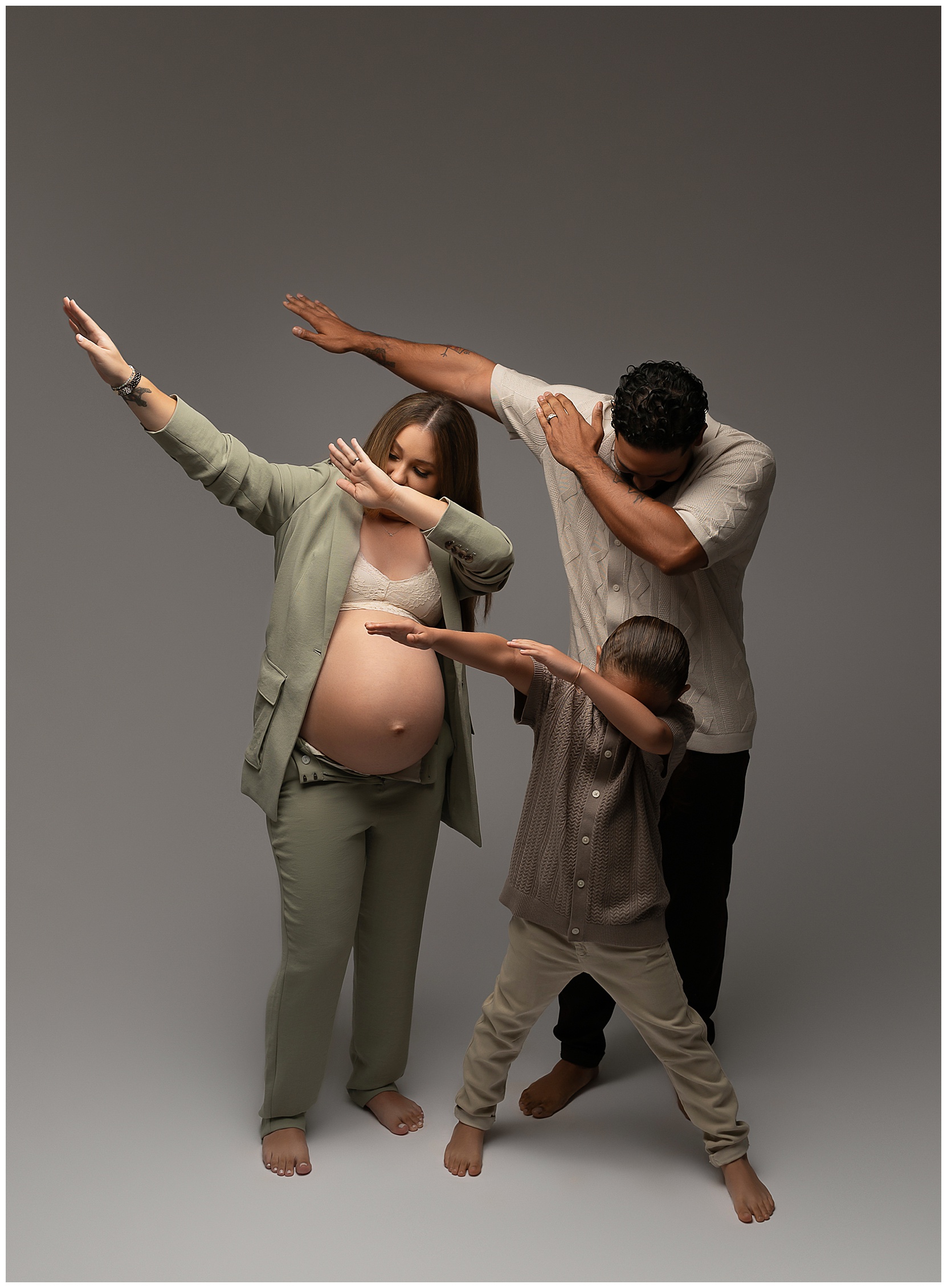 Family photo featuring a pregnant woman, man, and child doing a dabbing dance move.