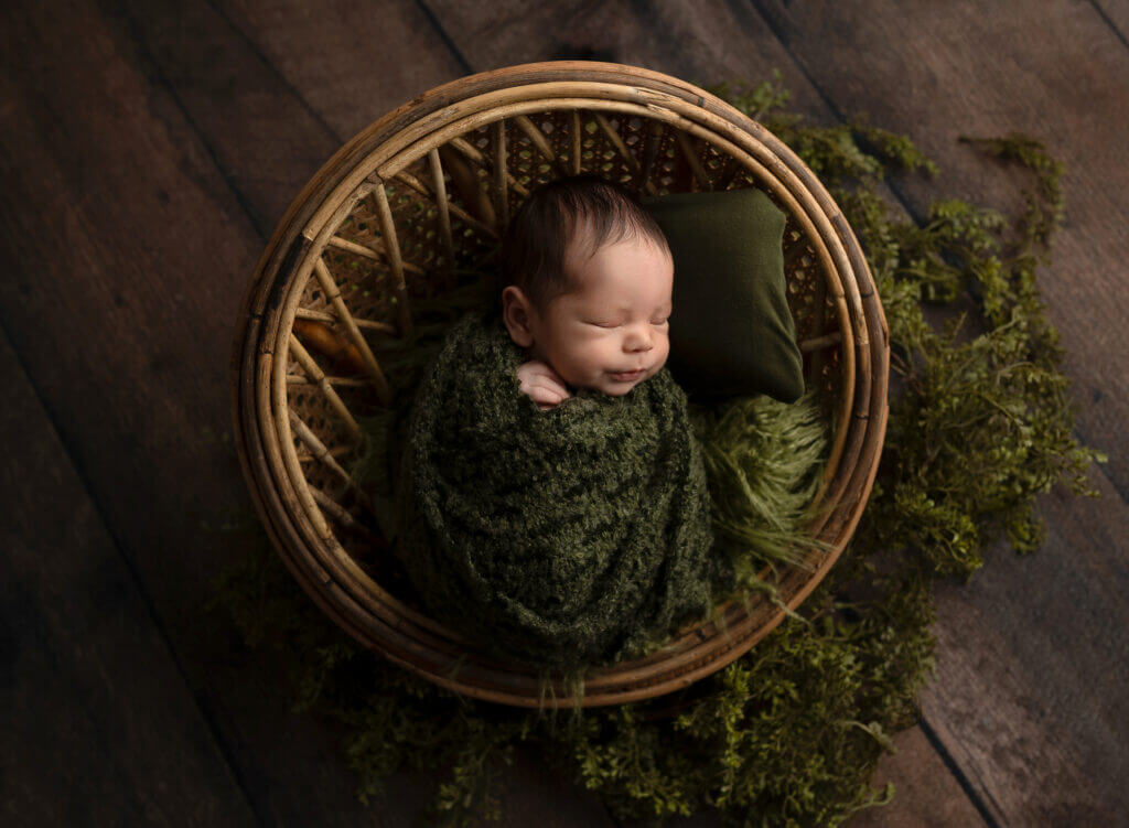 Nature themed newborn photos Austin using wooden props and organic green styling