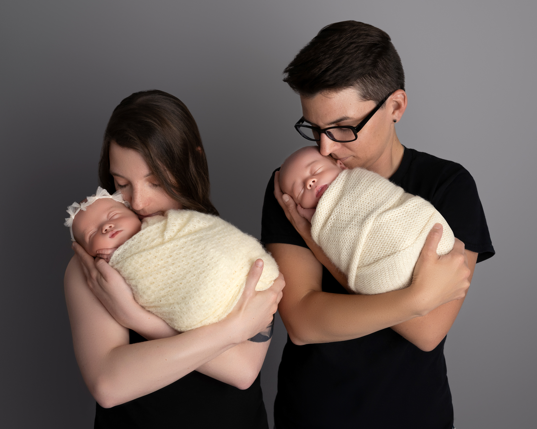Two moms hold their twin babies, one mom holding one baby. 