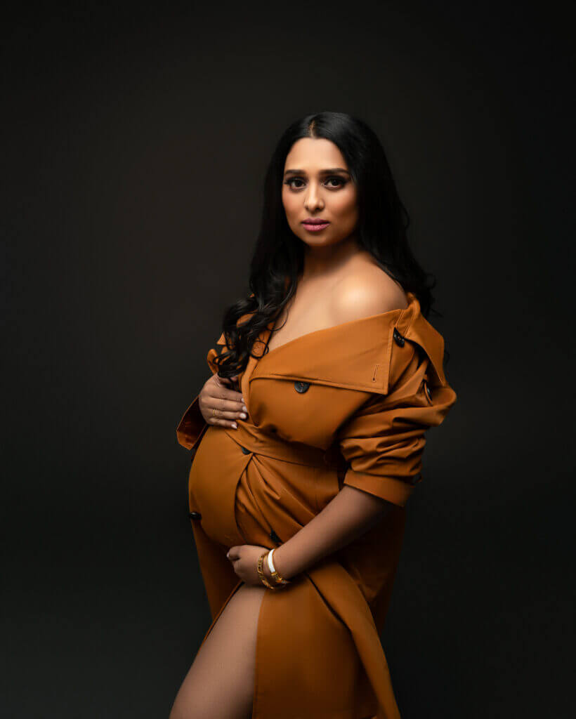 pregnant woman wearing brown pea coat off the shoulder during editorial maternity photoshoot