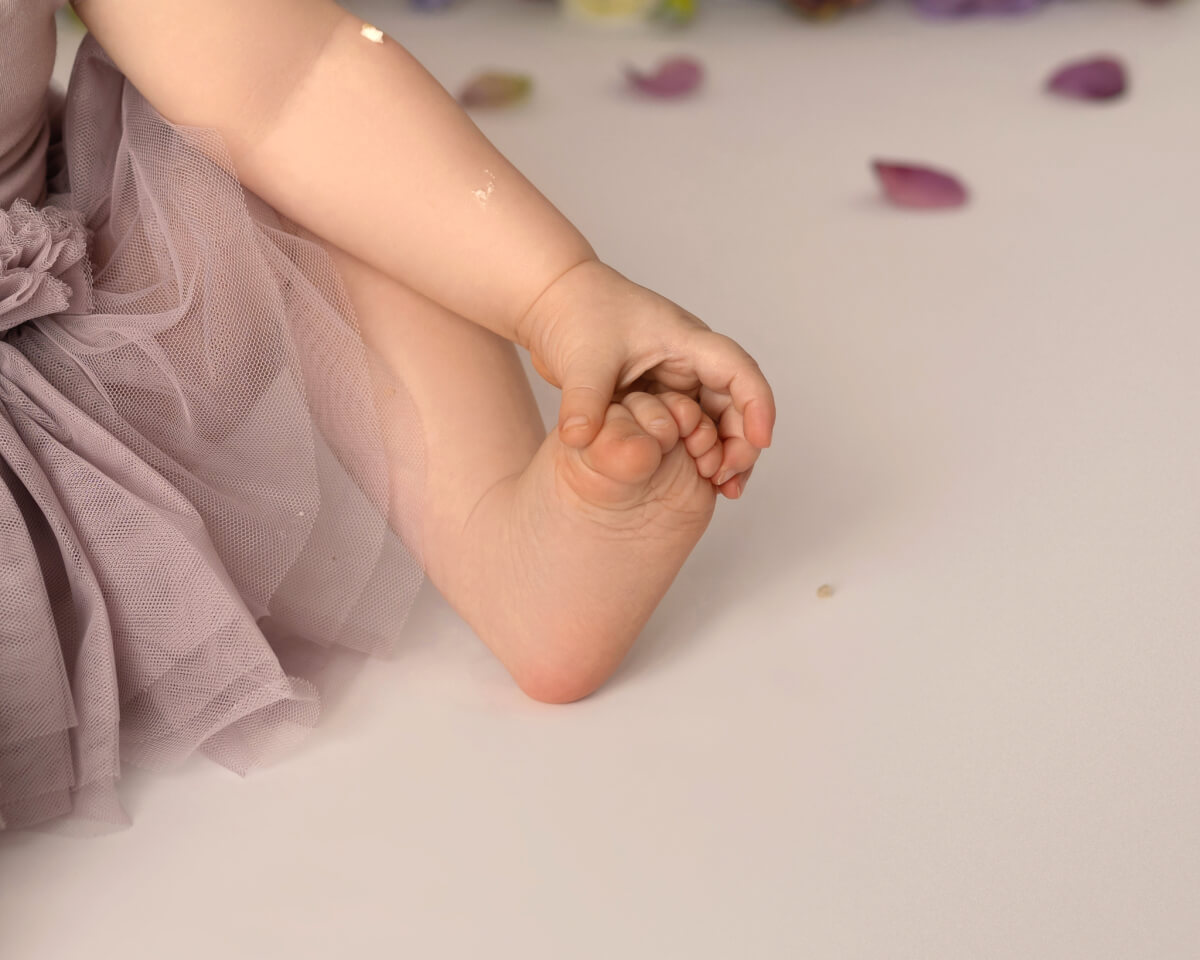 A close up photo of a baby holding onto it's foot. 