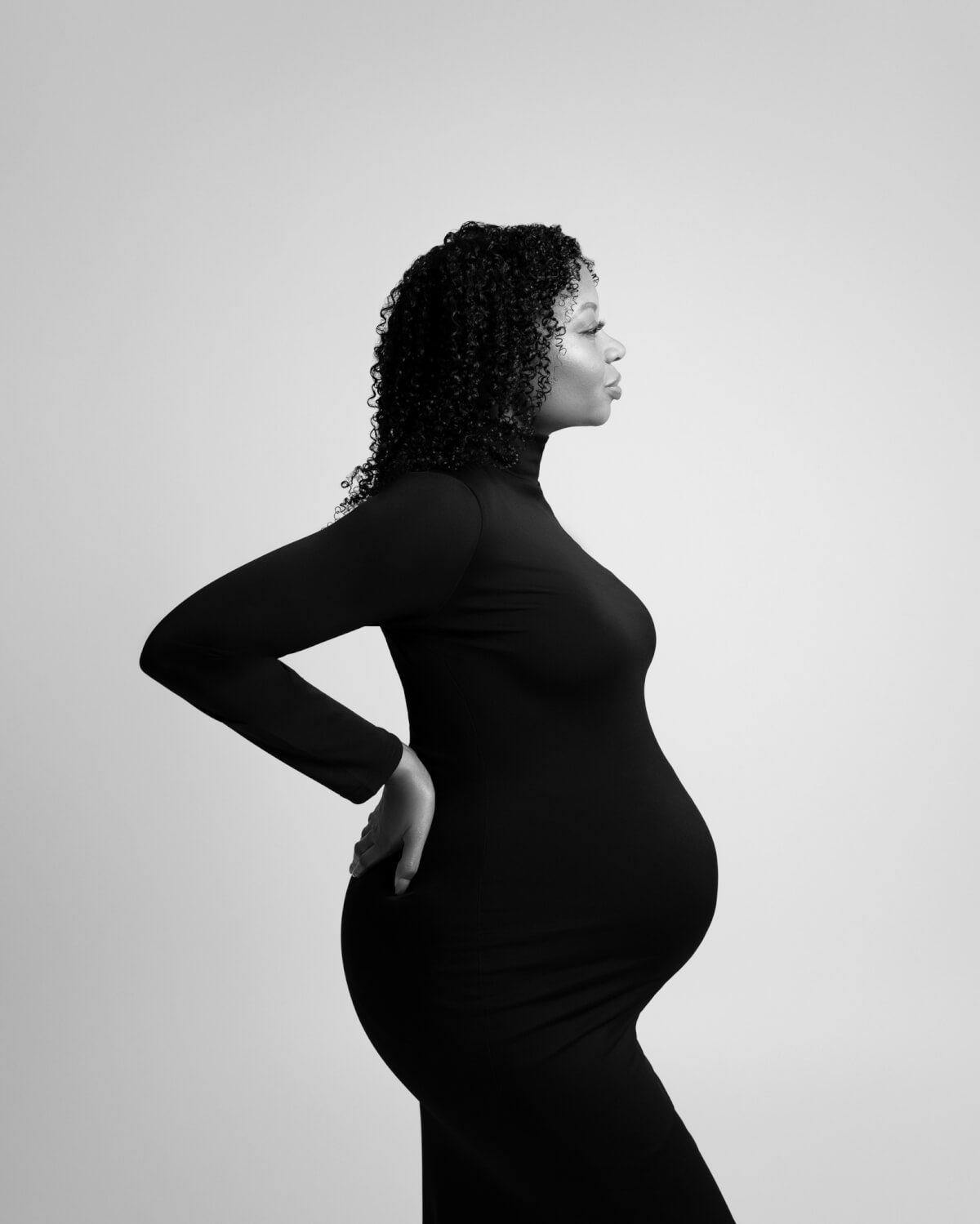 A high end maternity portrait of a pregnant woman in a black gown. 