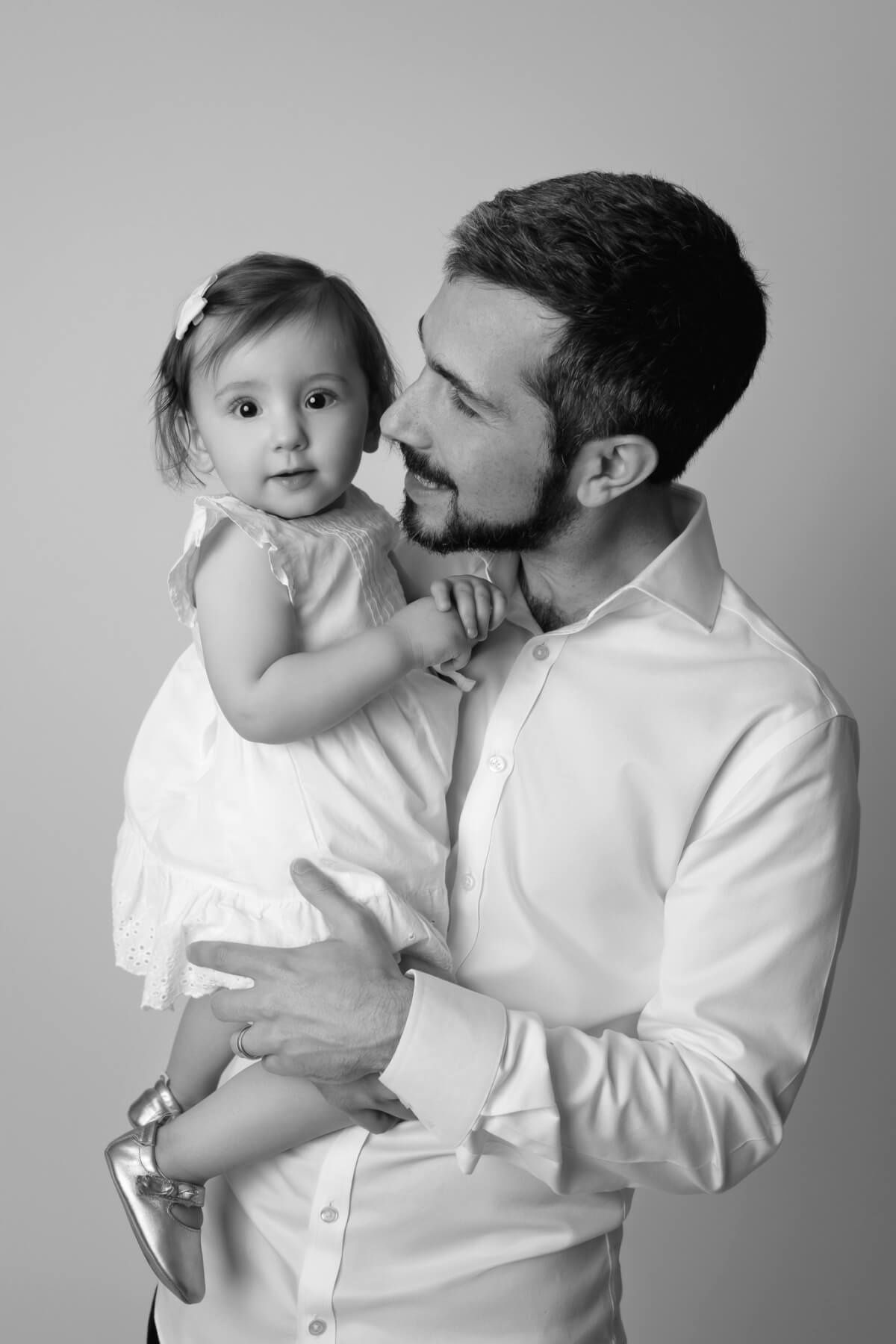 A man holds a one year old baby at her milestone photography session 