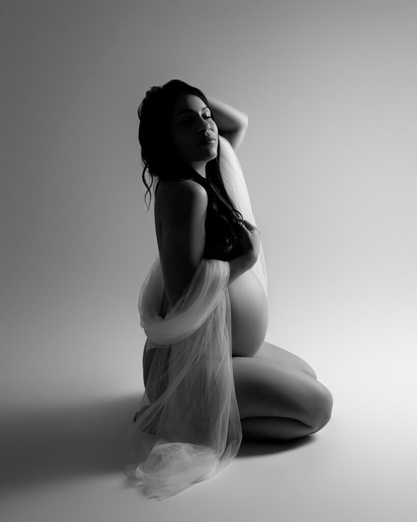 woman with white silk fabric kneeling for maternity photoshoot in austin