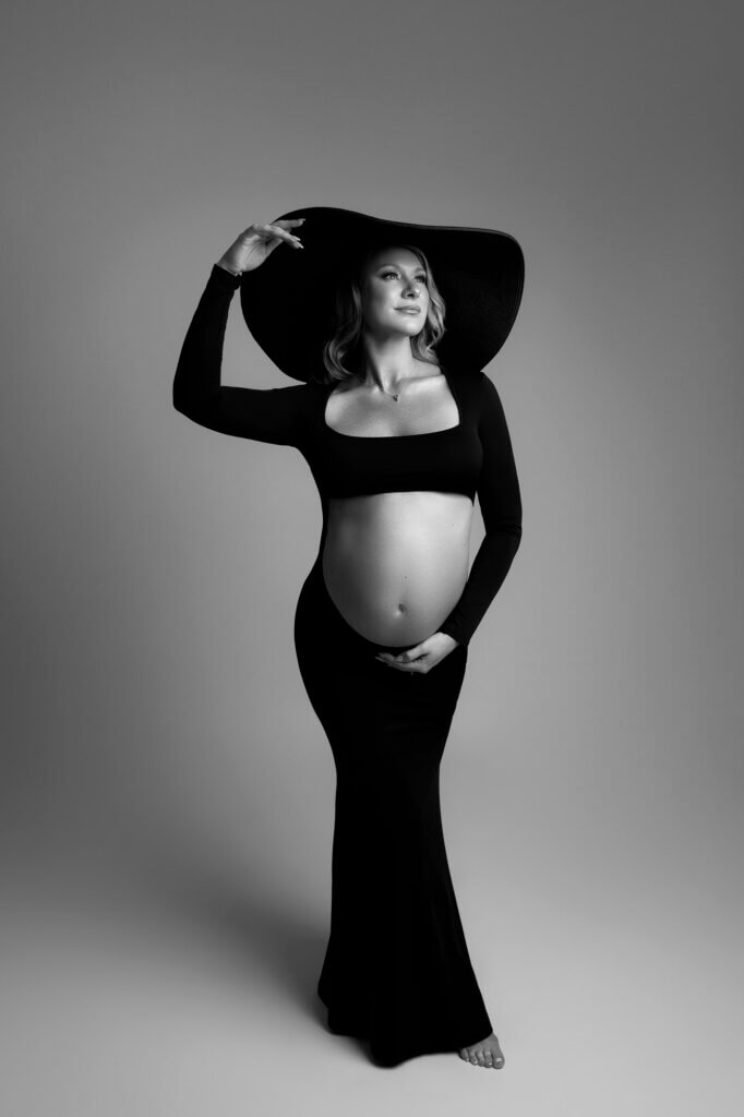 powerful pregnancy pose open belly black fitted dress black floppy hat
