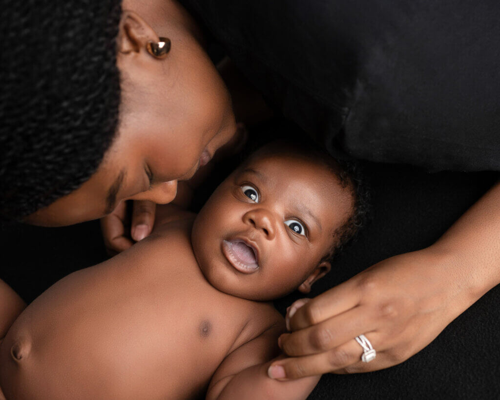 mom kissing newborn baby boy
