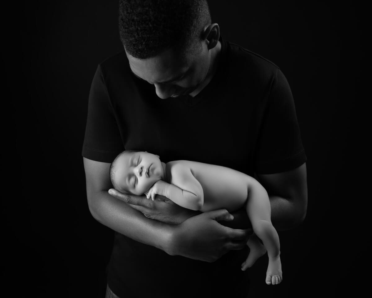 black and white dad holding new baby in arms