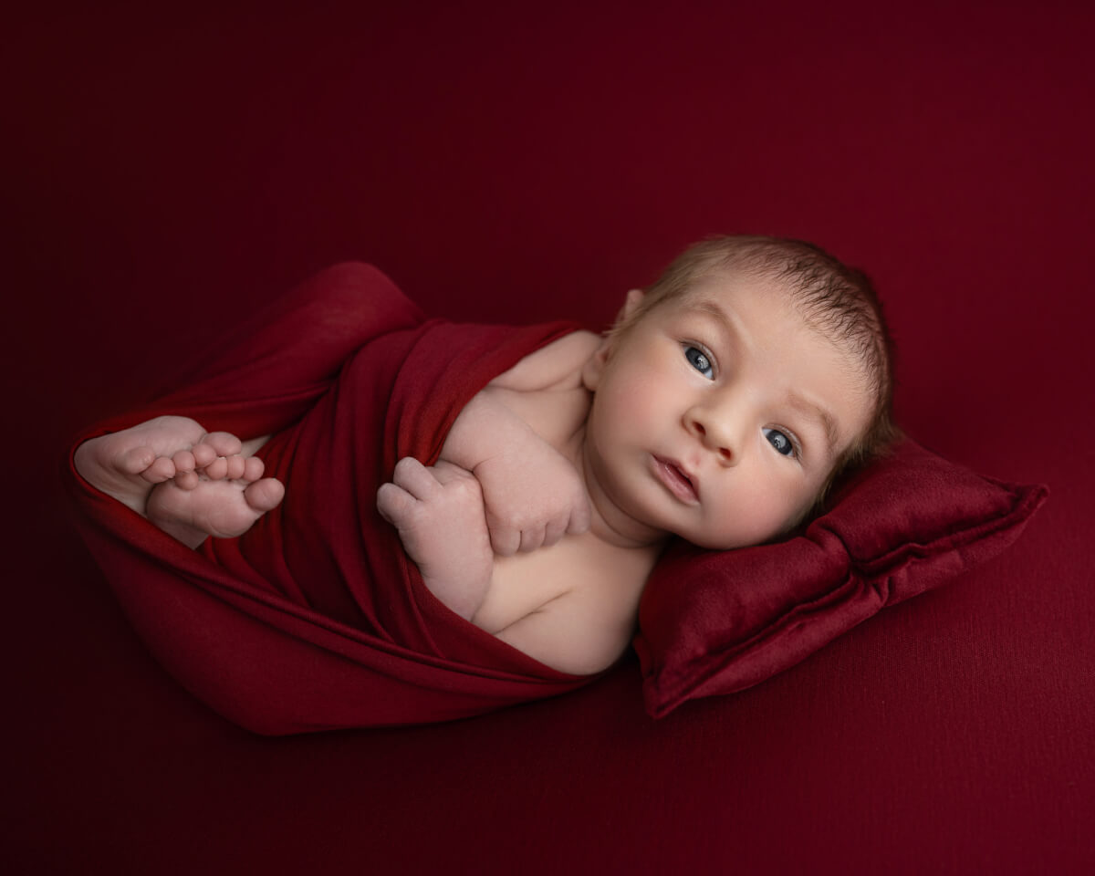 wake baby swaddled in red laying on red blanket