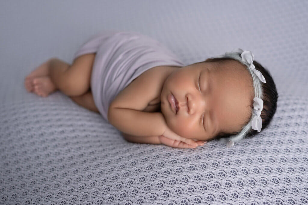 baby girl sleeping on purple textured blanket with purple headband