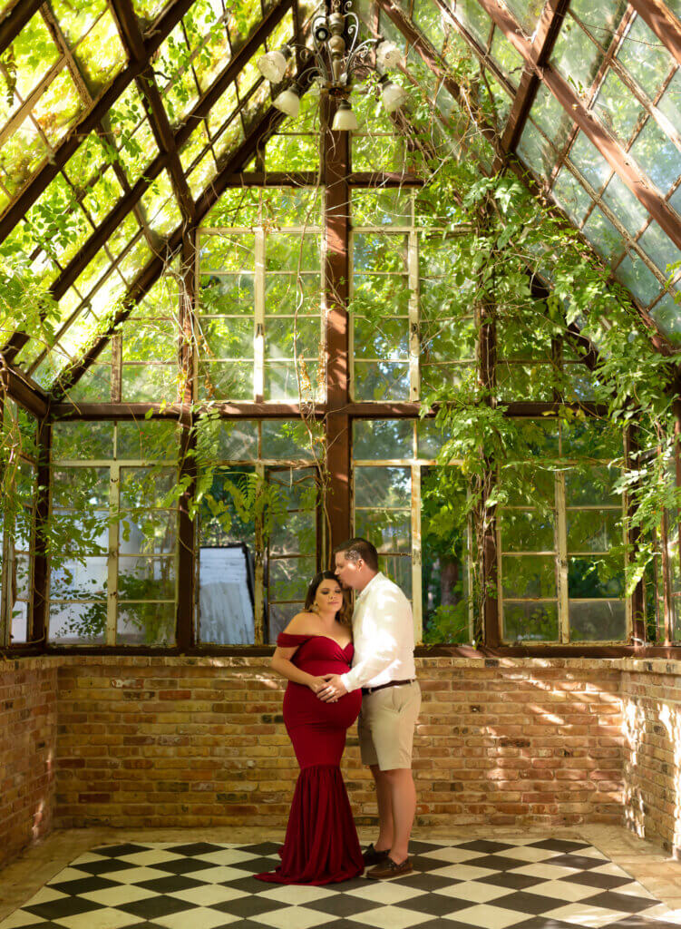 maternity photos Sekrit Theater Austin Texas greenhouse covered in vines red gown checkerboard floor